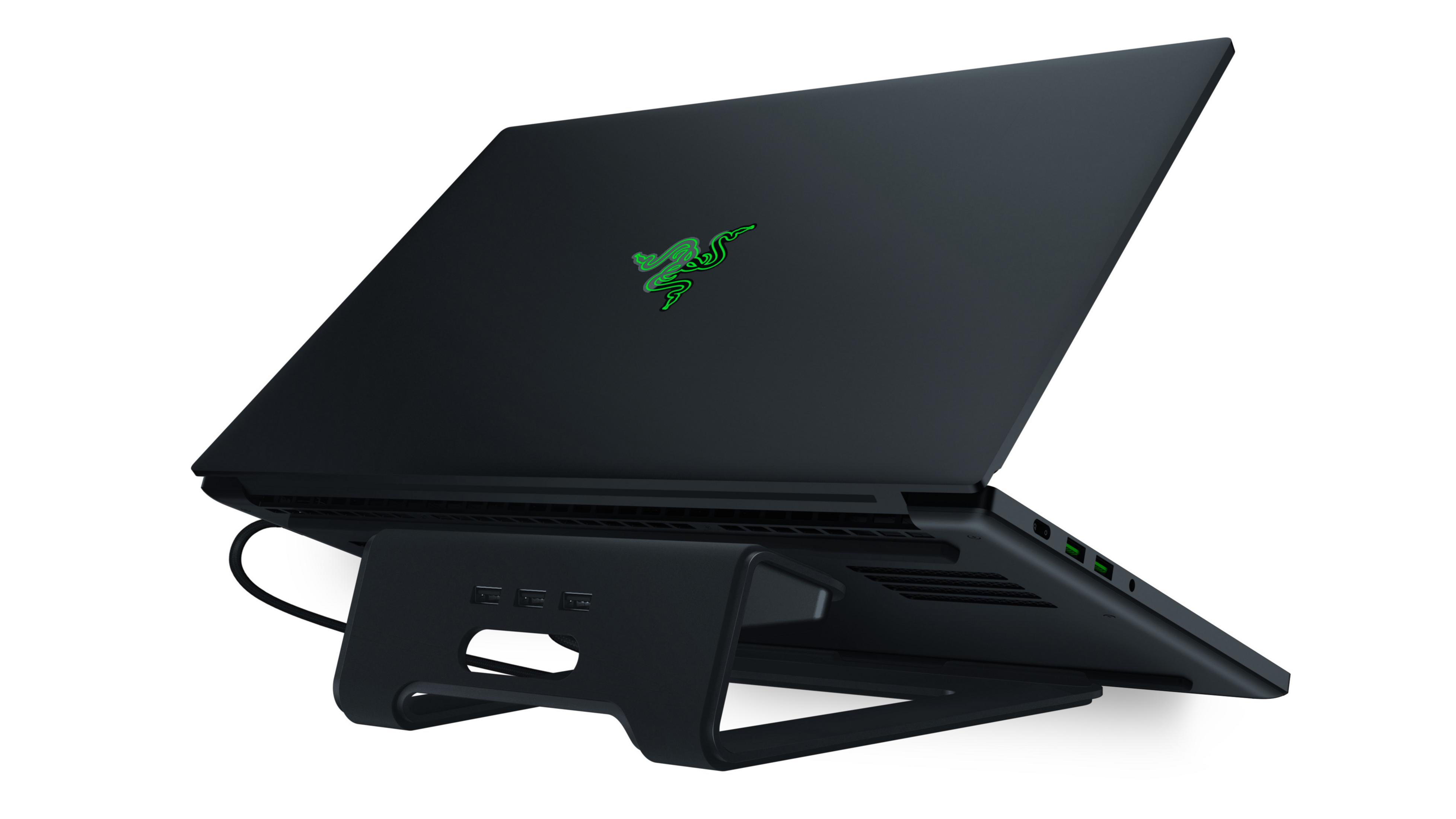 Czarny laptop na czarnym stojaku, uchylony, pokazujący tył z zielonym logo. Białe tło.