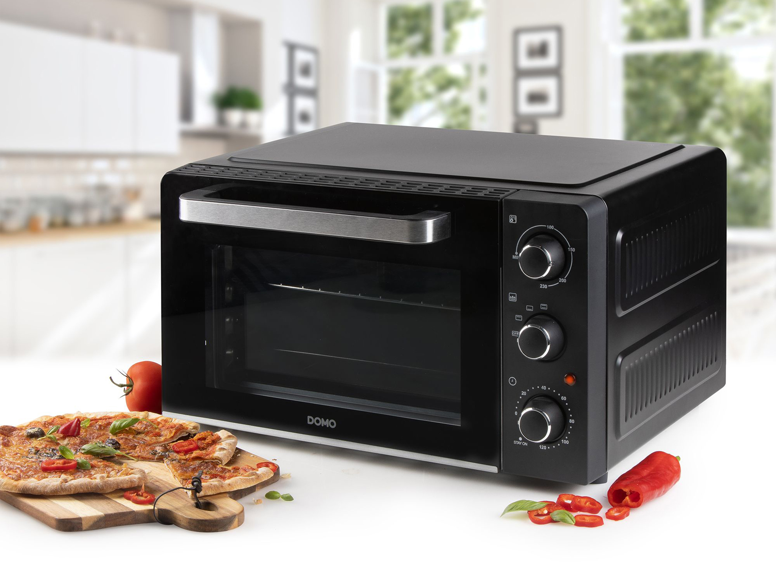 Forno nero con pizza e ingredienti su un tagliere di legno, con sfondo cucina.