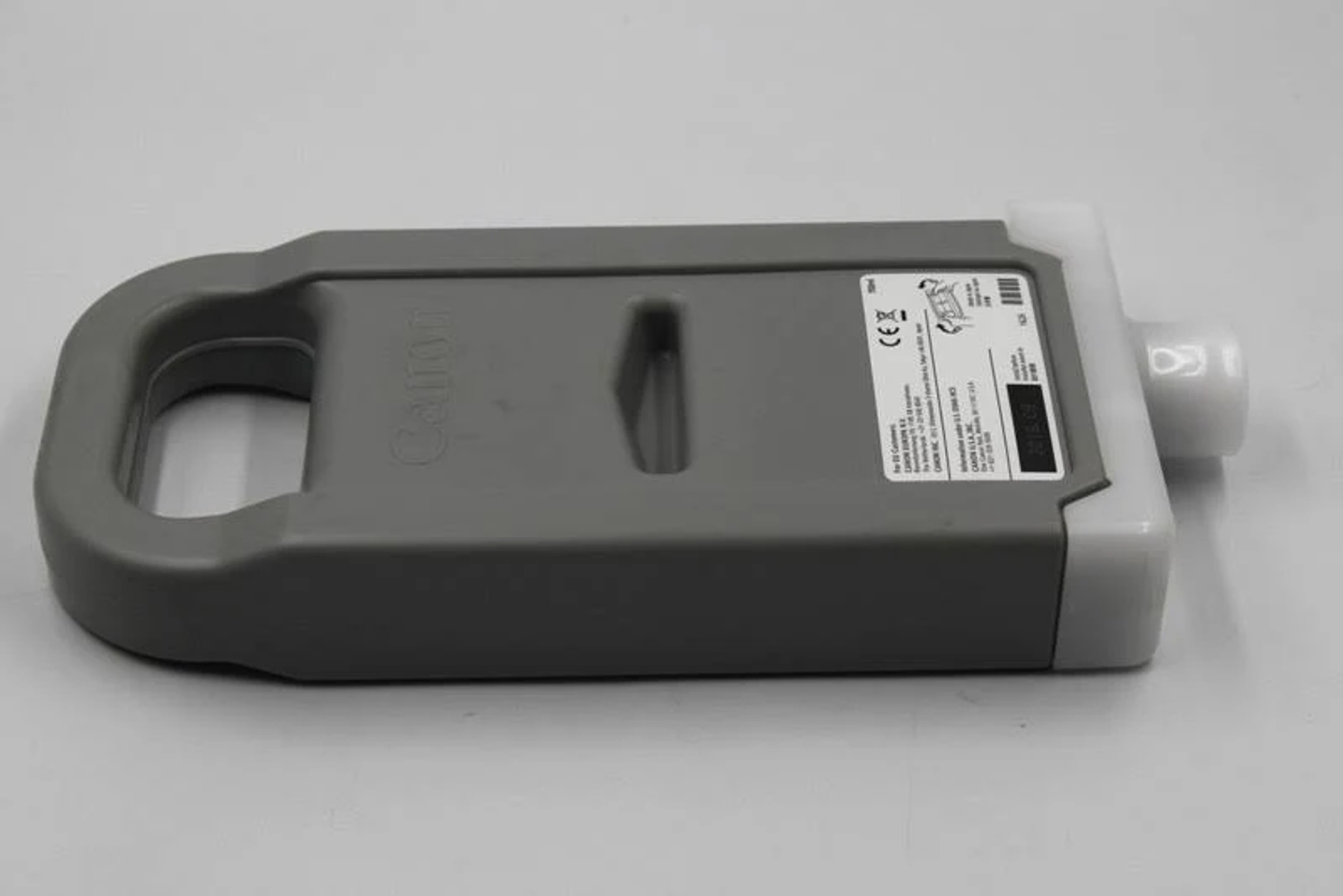 Serbatoio inchiostro grigio Canon con ugello bianco e maniglia. Il serbatoio ha un'etichetta con testo.