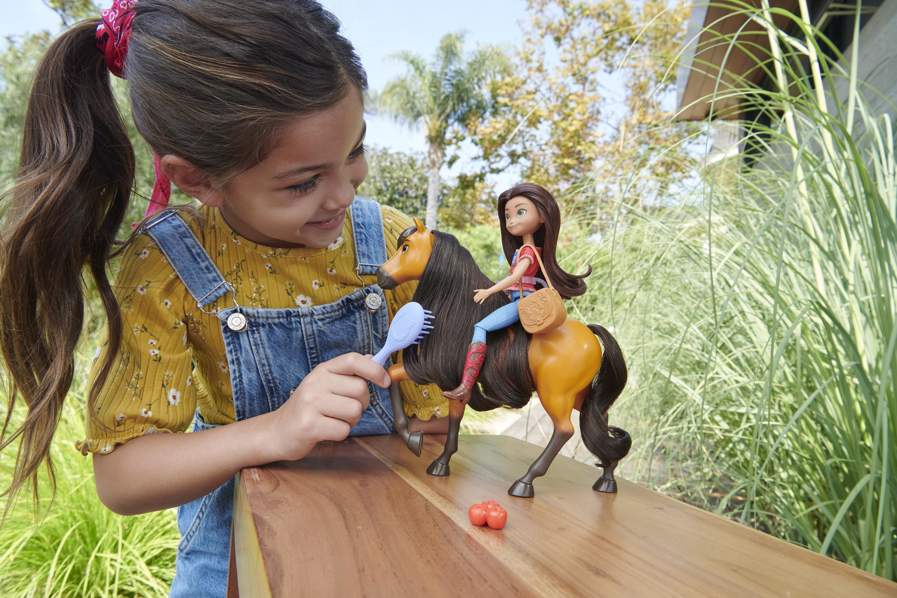 Dziewczynka z lalką i zabawką koniem. Czesze włosy zabawki.
