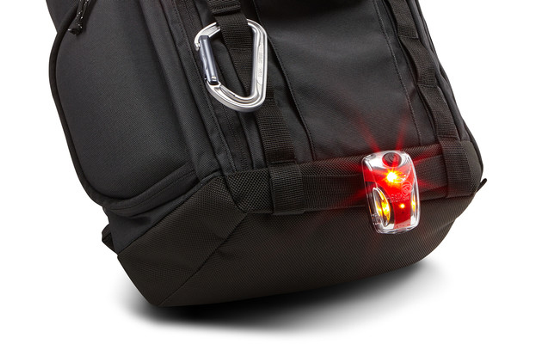 Eine schwarze Tasche mit rotem Licht. Ein silberner Karabinerhaken hängt an der Tasche.