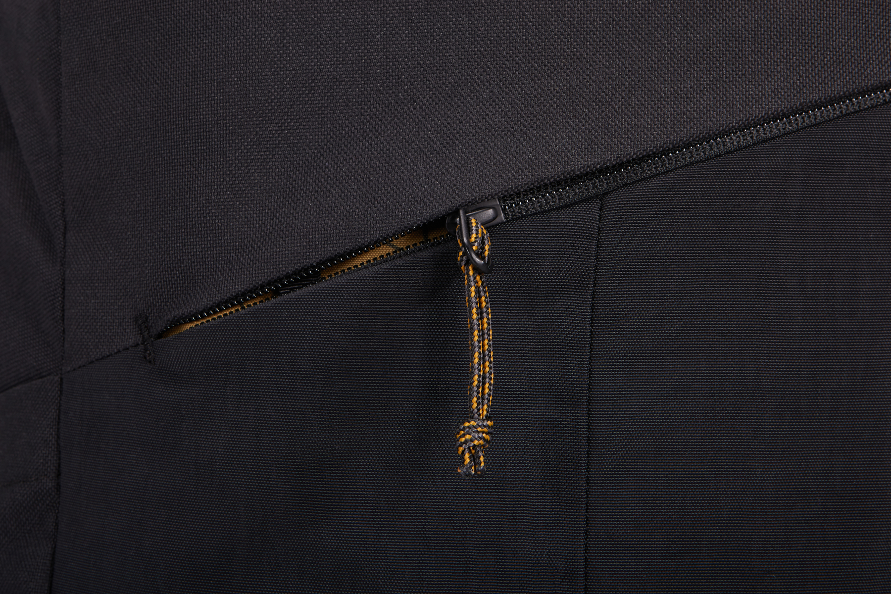 Primo piano di una borsa nera con cerniera e tiretto giallo e nero.