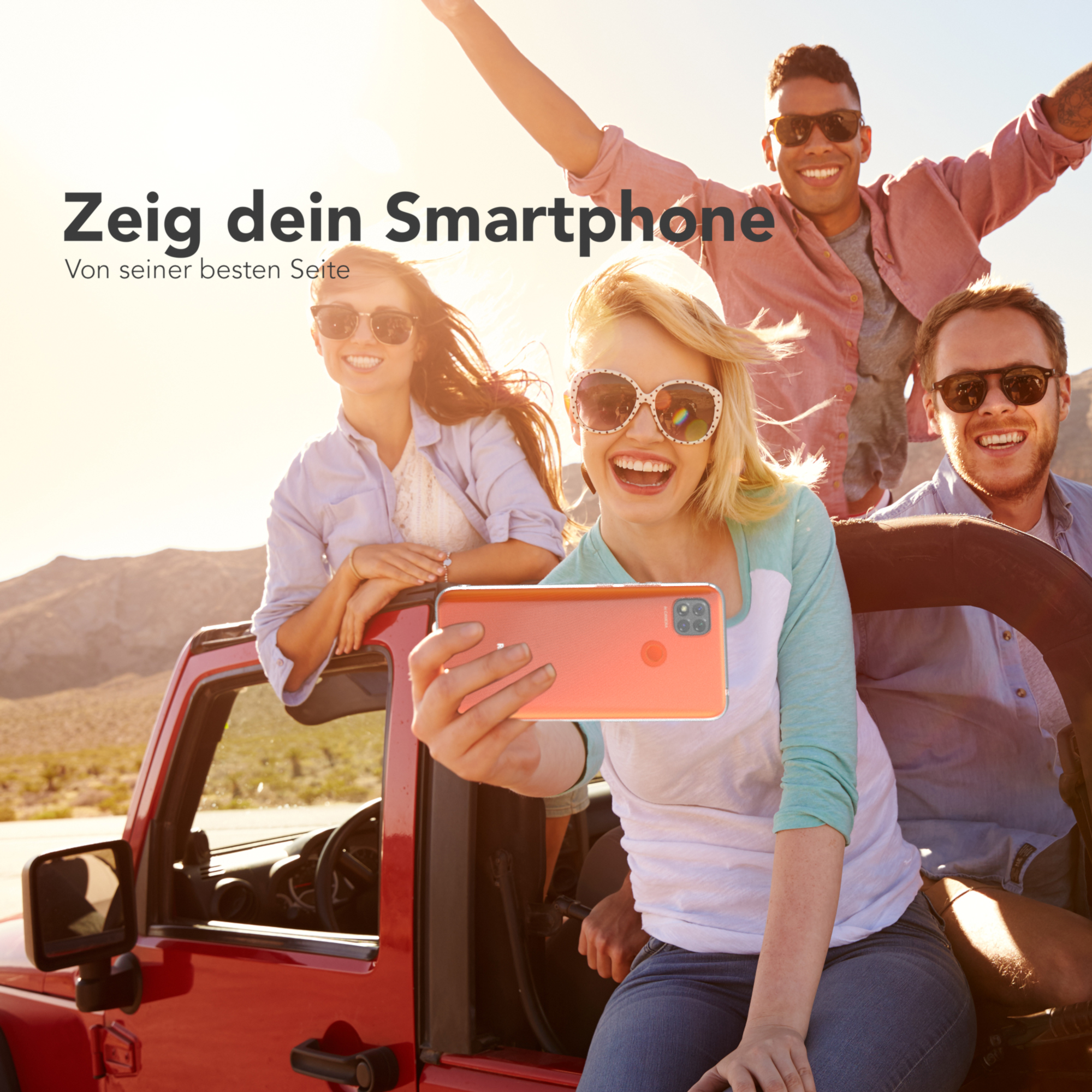 Gruppe von Leuten in einem roten Auto, die ein oranges Telefon für ein Selfie halten. Glücklicher, sonniger Tag.