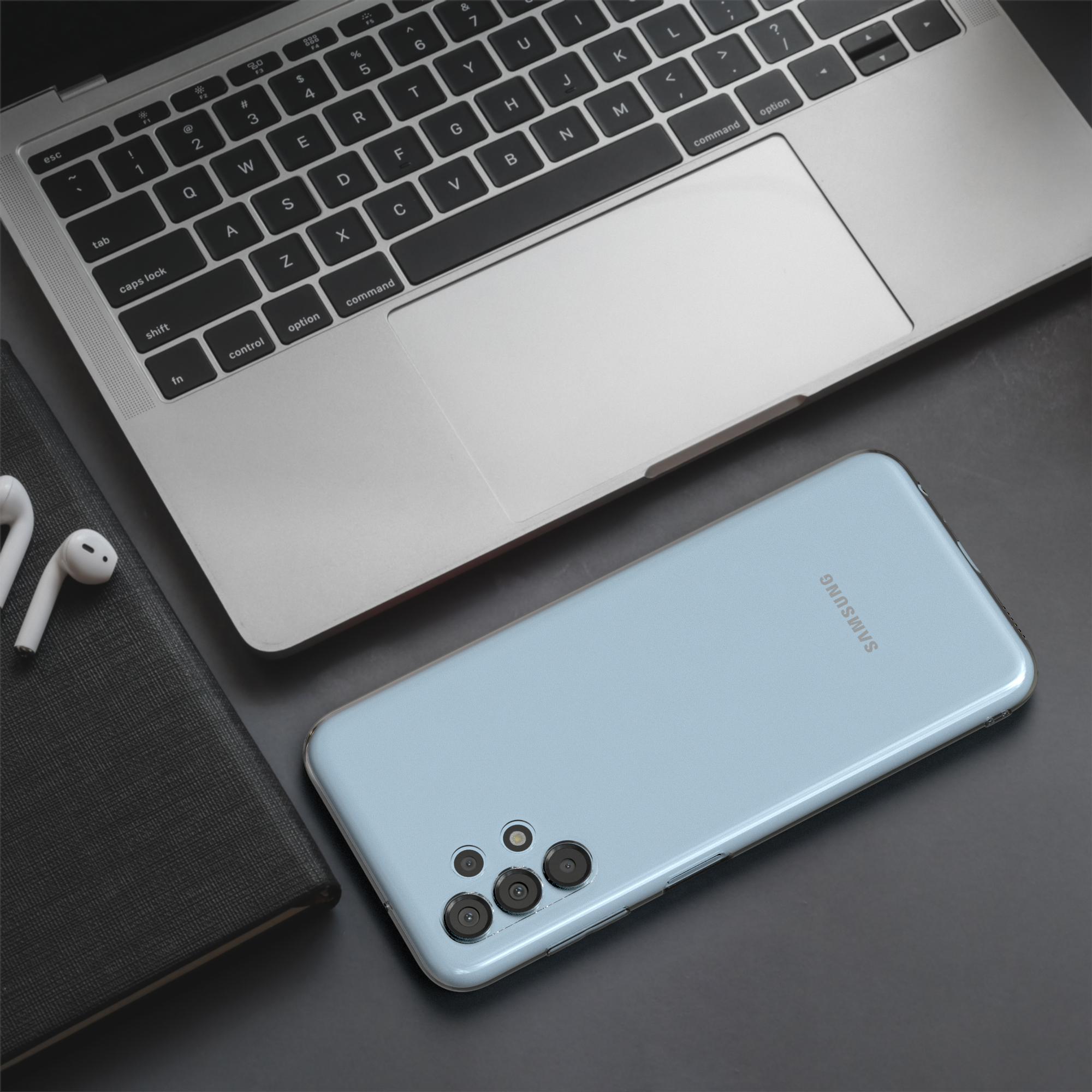 Laptop, Telefon und Ohrh örer auf dunkler Oberfläche. Das Telefon ist hellblau.