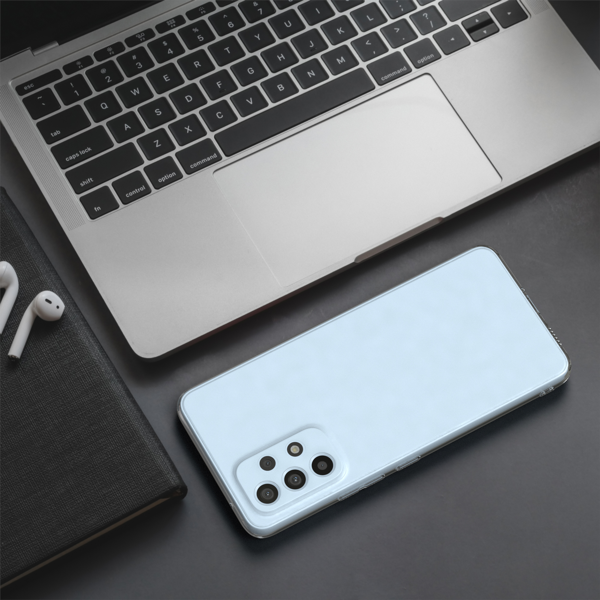 Smartphone, Laptop und Zubehör auf dunkler Oberfläche, bilden ein Tech-Setup.