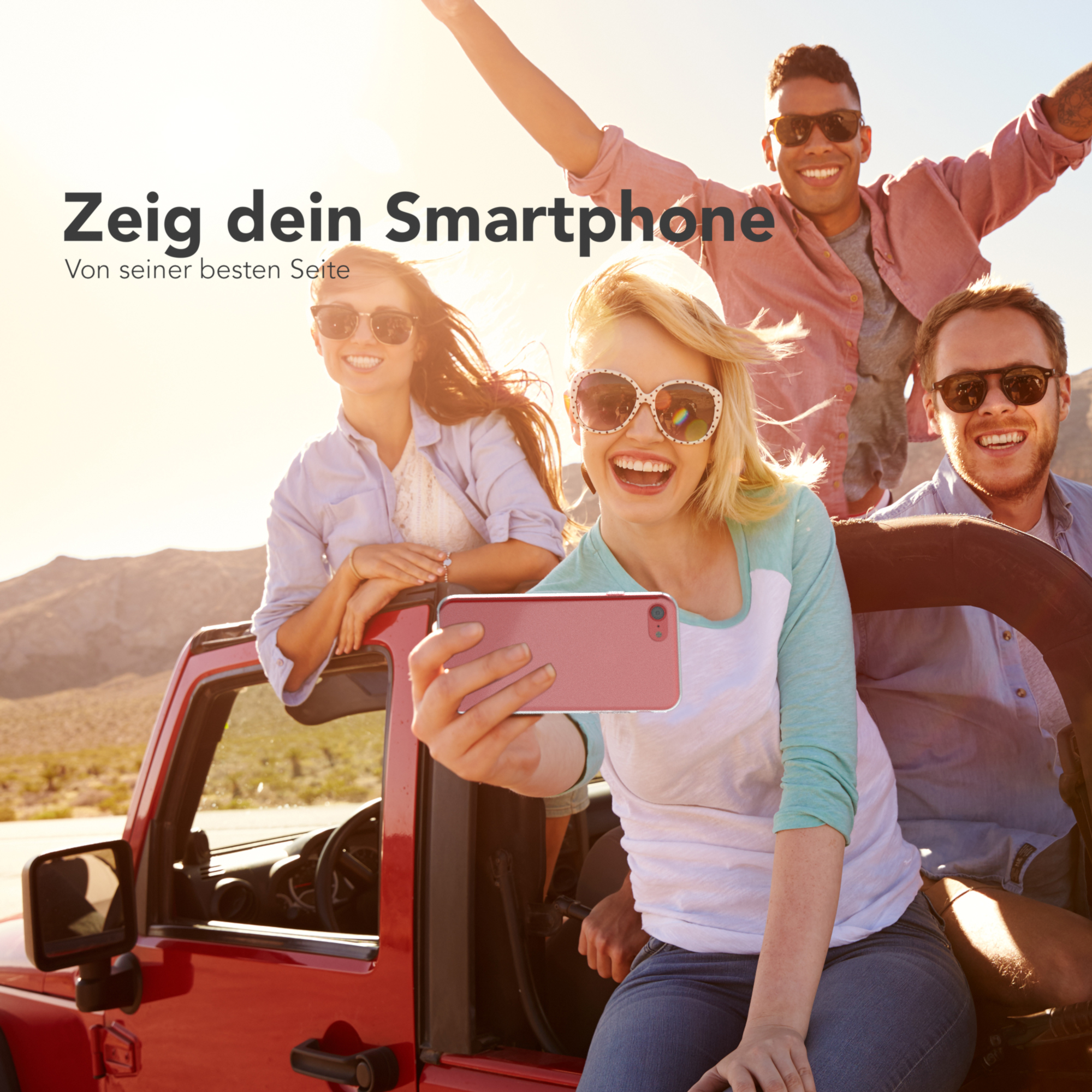 Gruppe von vier Personen in einem roten Jeep, die ein Selfie machen. Sie lächeln und scheinen sich zu amüsieren.