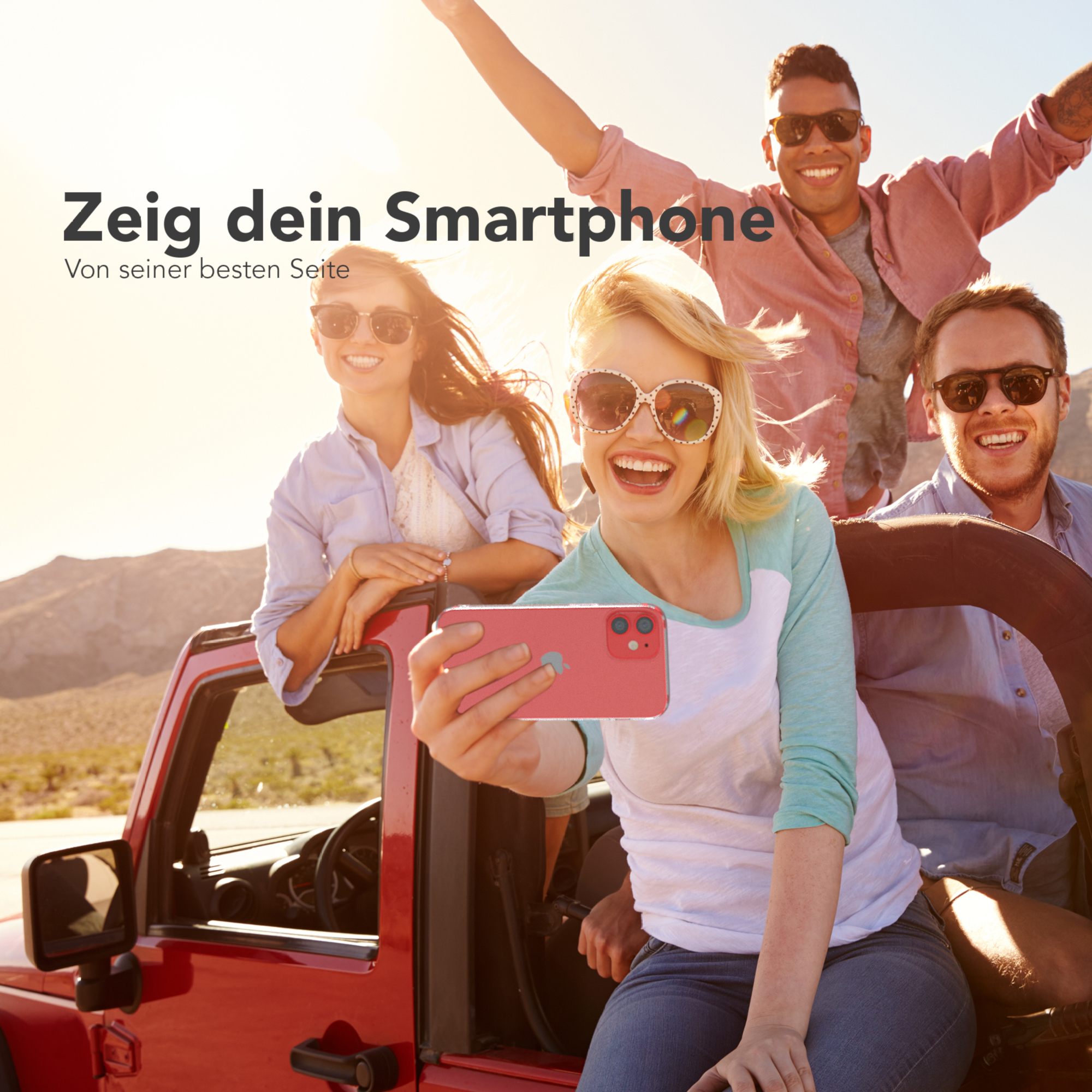 Vier Personen in einem roten Jeep machen ein Selfie. Einer hält ein rosa Handy. Sonniger Außenbereich.