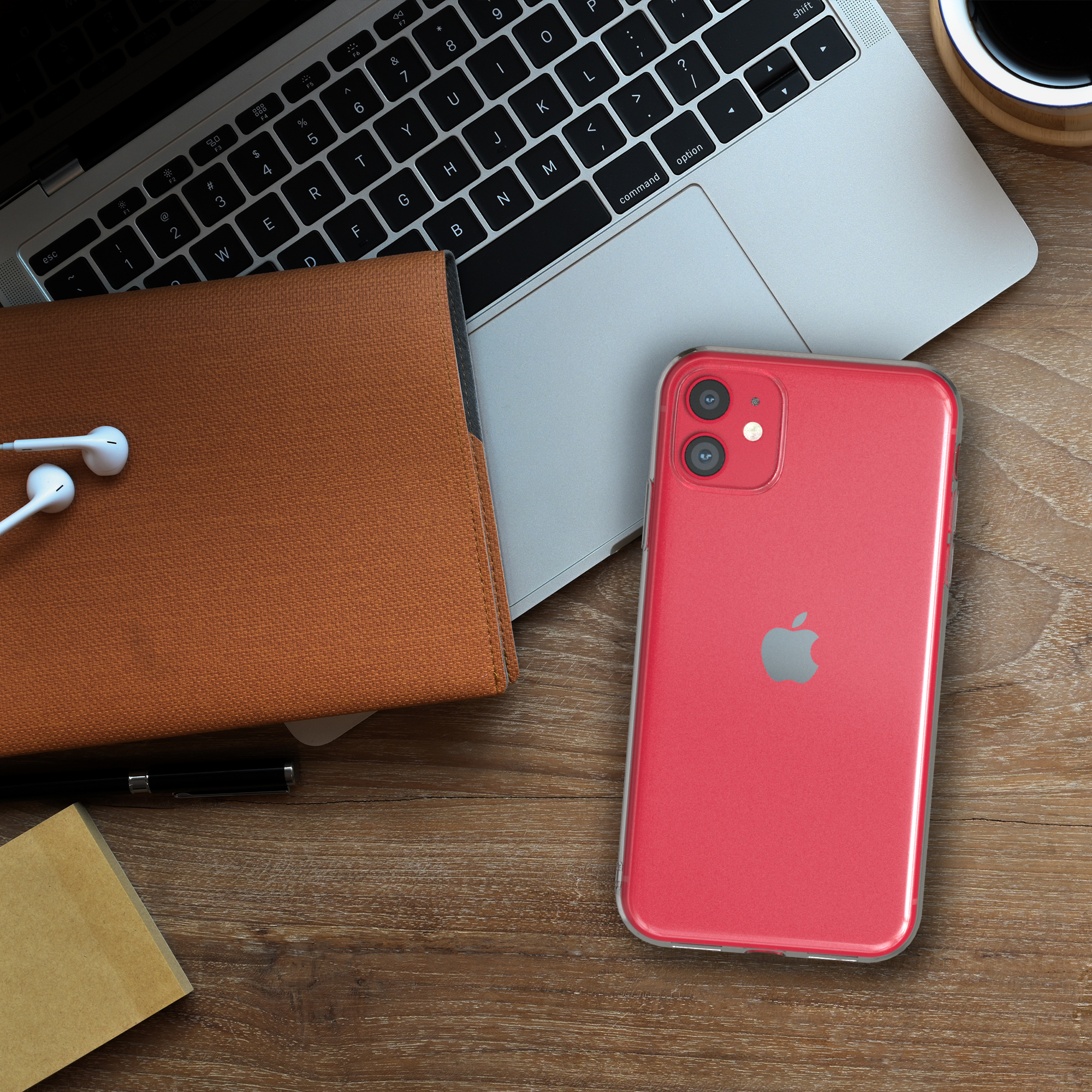 Ein rotes Telefon mit einer durchsichtigen Hülle auf einem Holztisch. Ein Laptop, Kopfhörer und ein Notizbuch sind in der Nähe.