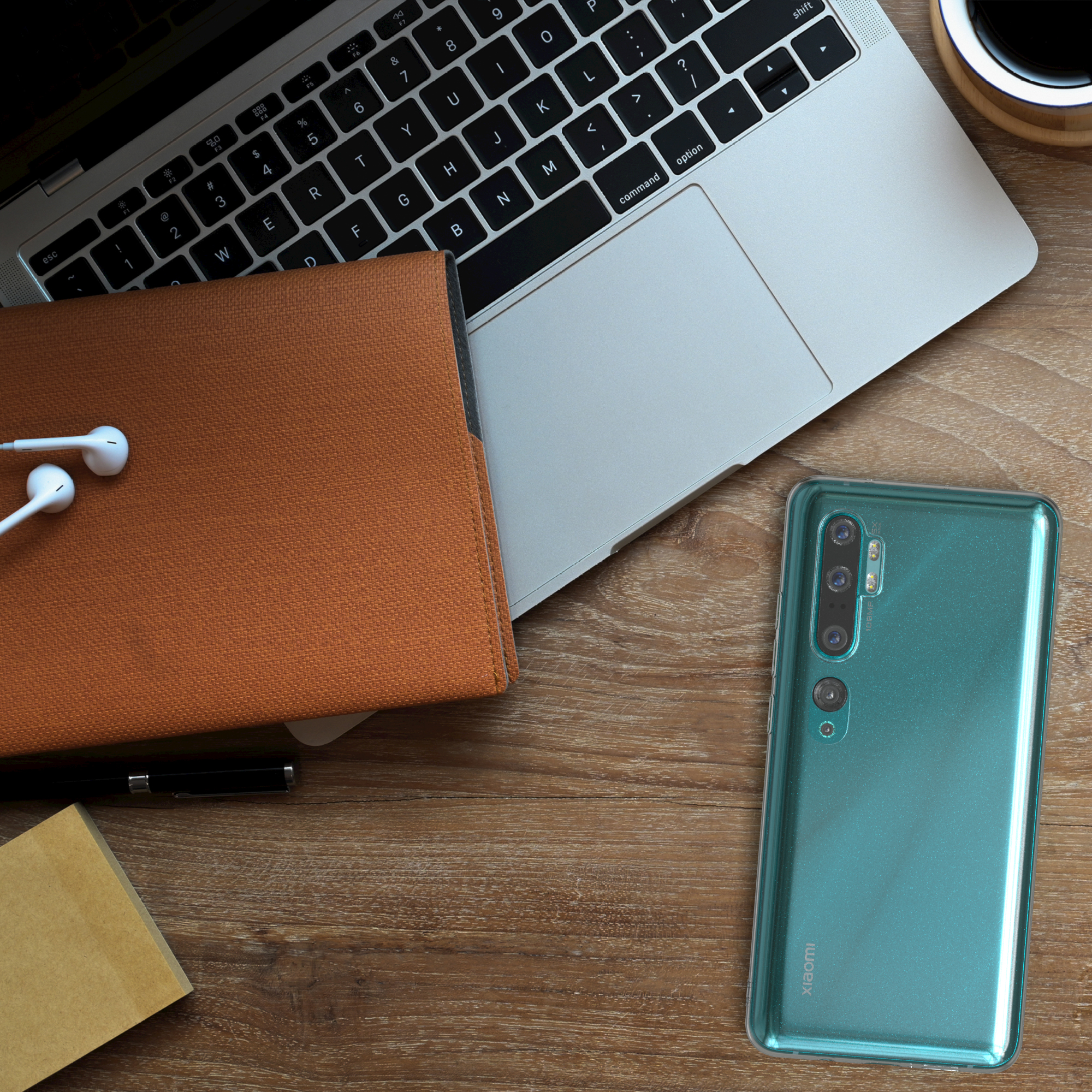 Laptop, Telefon und Zubehör auf einem Holzschreibtisch. Telefon ist grün.