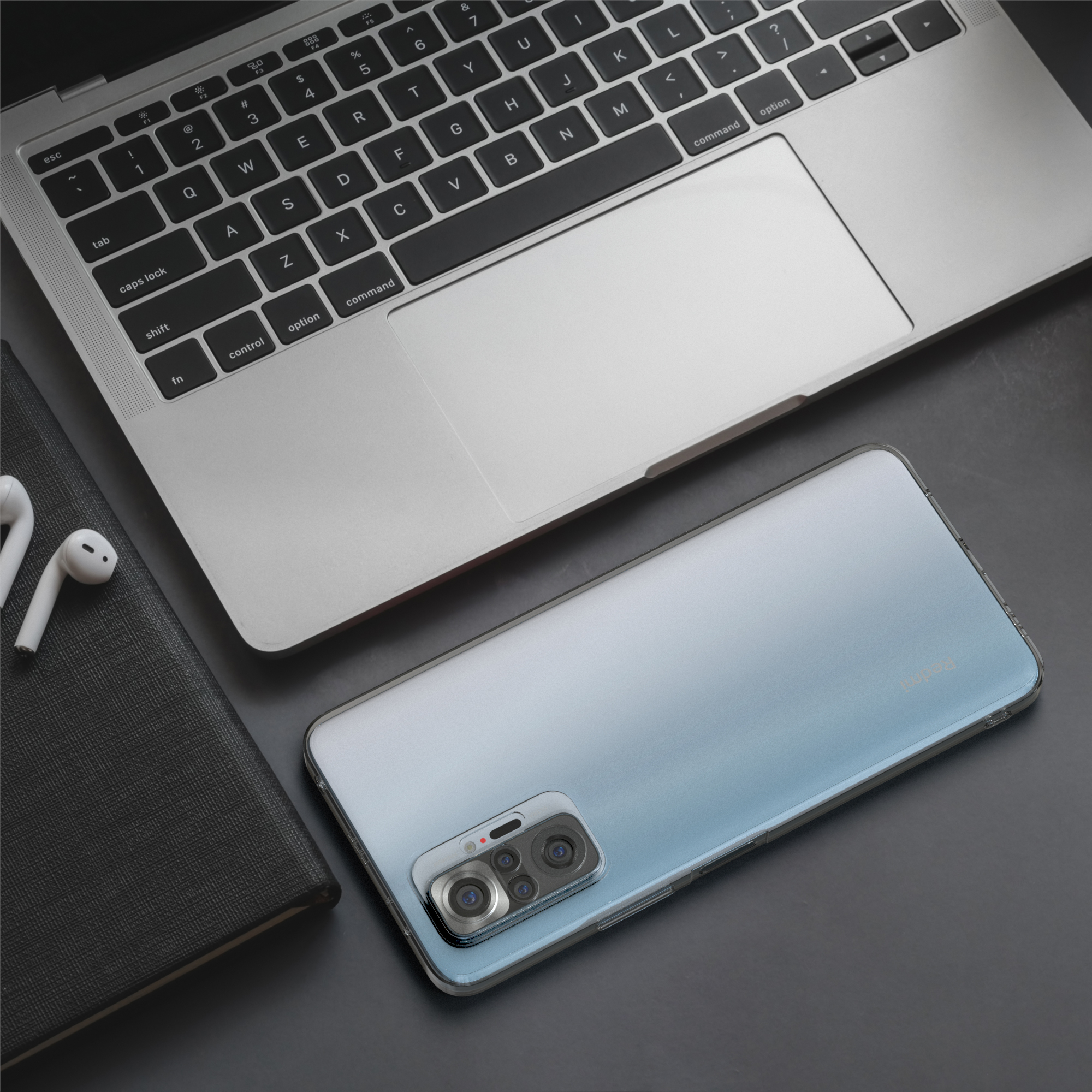 Ein Telefon auf einem Schreibtisch mit einem Laptop, Kopfhörern und einem Notizbuch.
