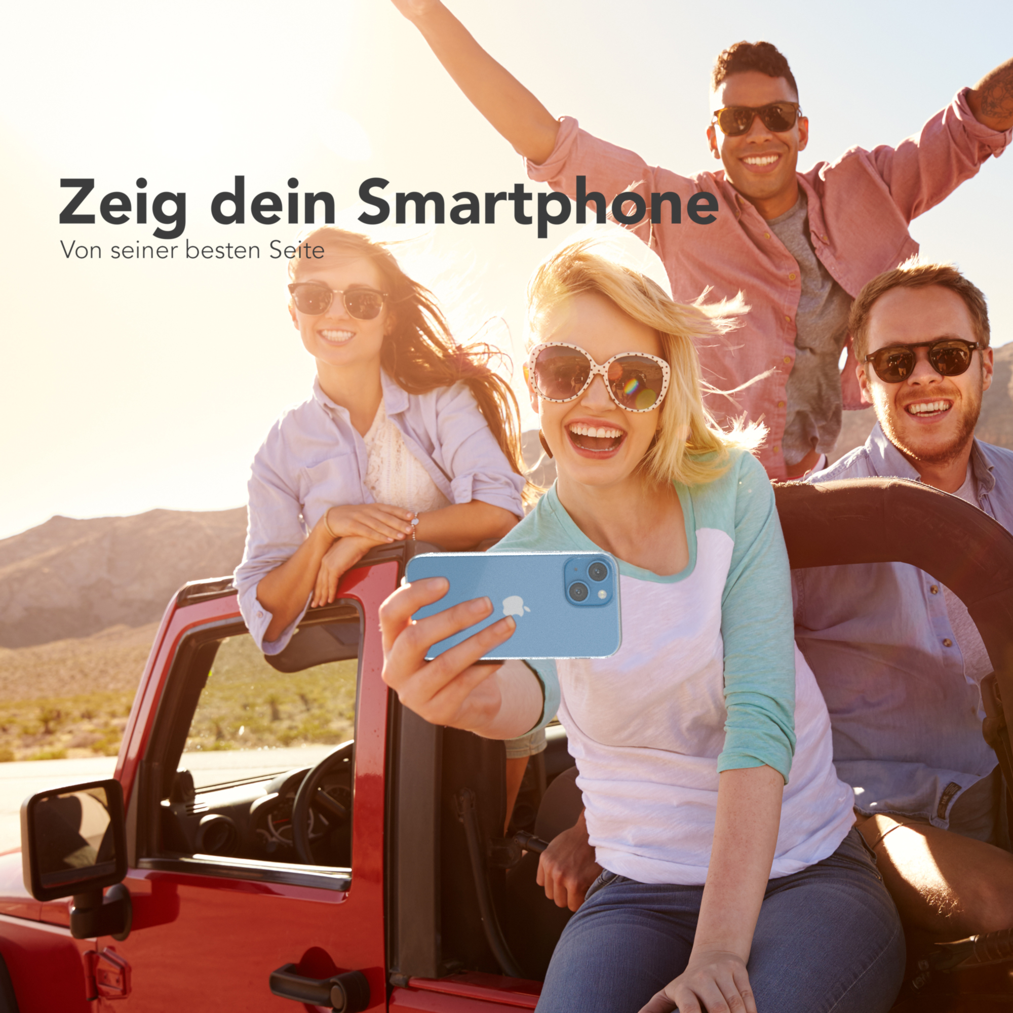 Eine Gruppe von vier Freunden macht ein Selfie. Die Person, die das Telefon hält, lächelt.