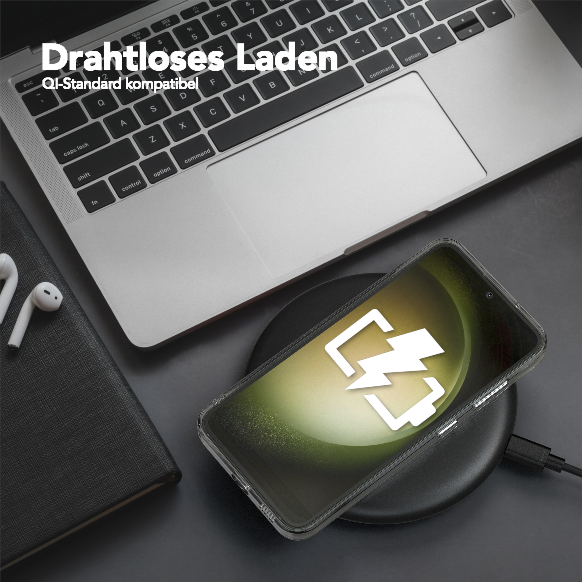 Ein Smartphone, das drahtlos auf einem schwarzen Pad geladen wird, neben einem Laptop.