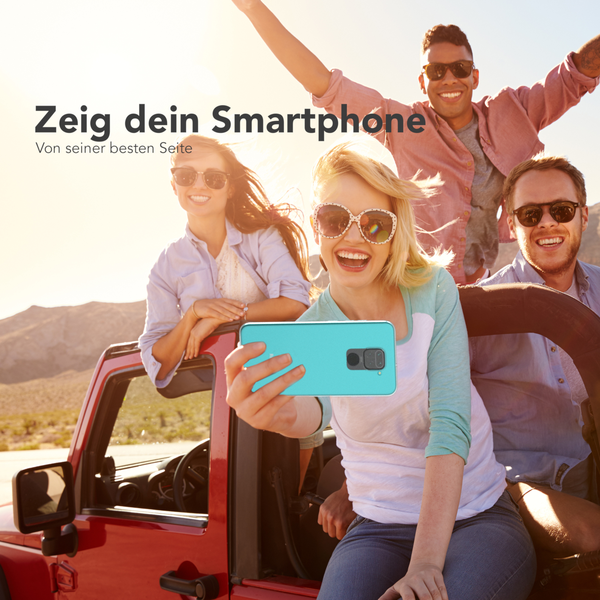 Vier Personen in einem roten Jeep machen ein Selfie mit einem Telefon. Die Sonne scheint im Hintergrund.