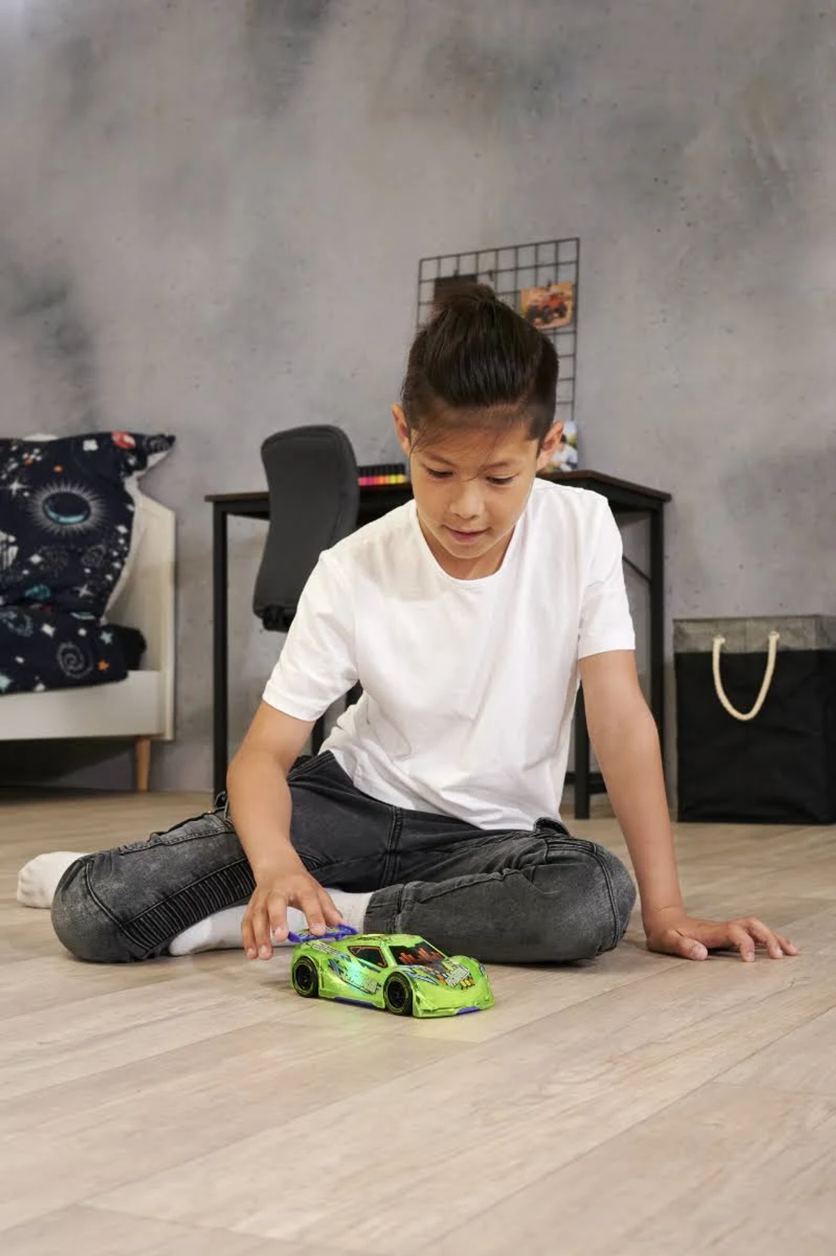 Chłopiec bawiący się zielonym samochodzikiem na podłodze.