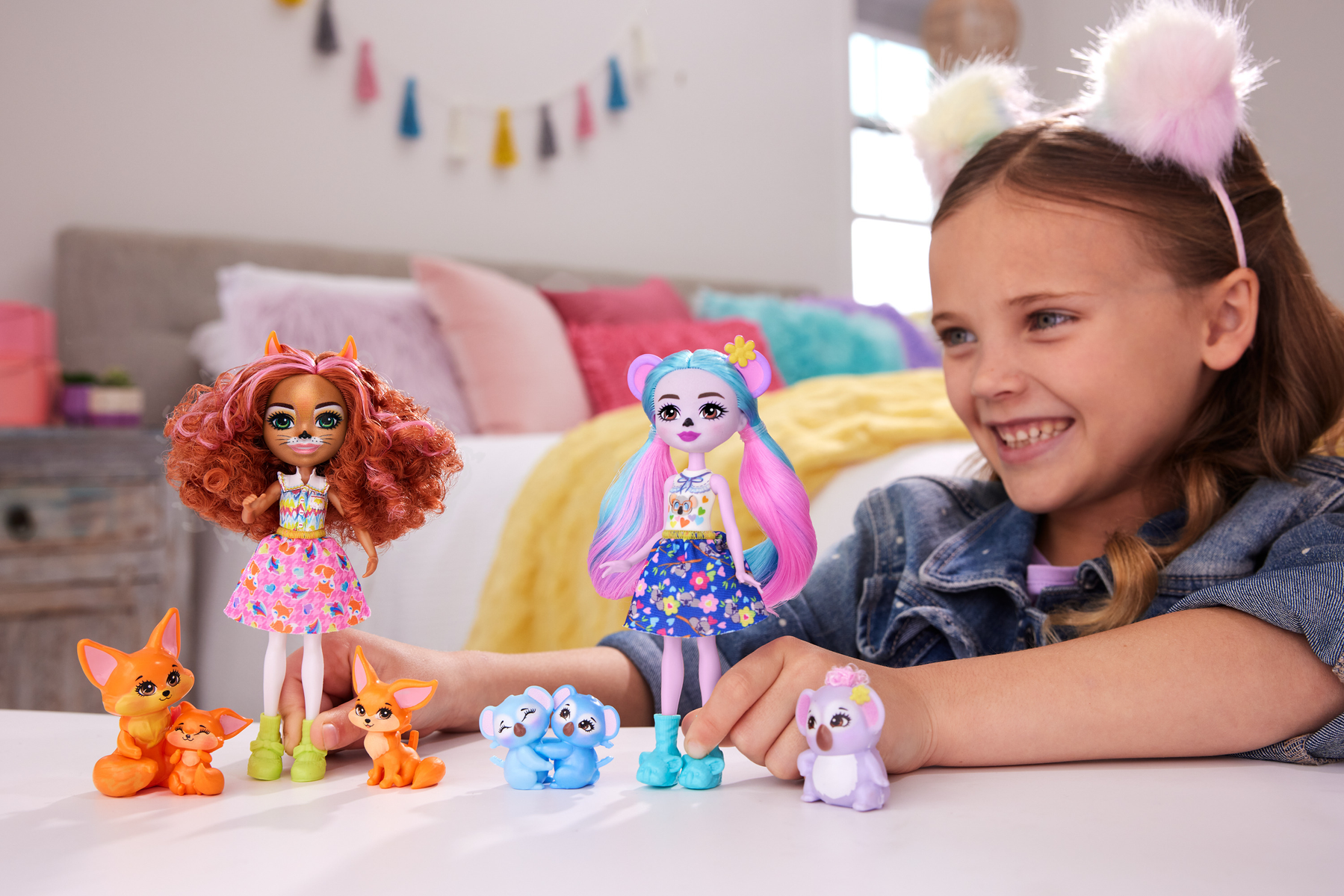Uśmiechnięta dziewczyna z lalkami i figurkami zwierząt przed sobą, lalki z kolorowymi włosami.
