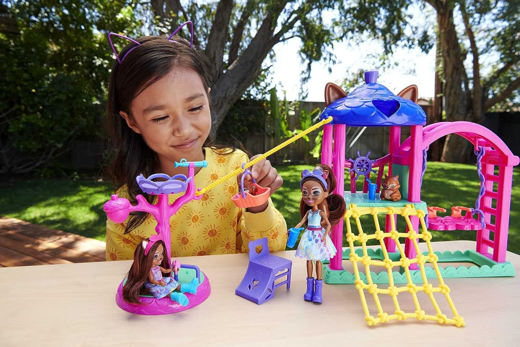 Dziewczynka bawiąca się lalkami na zestawie do zabawy, lalki w zestawie, słoneczne tło.