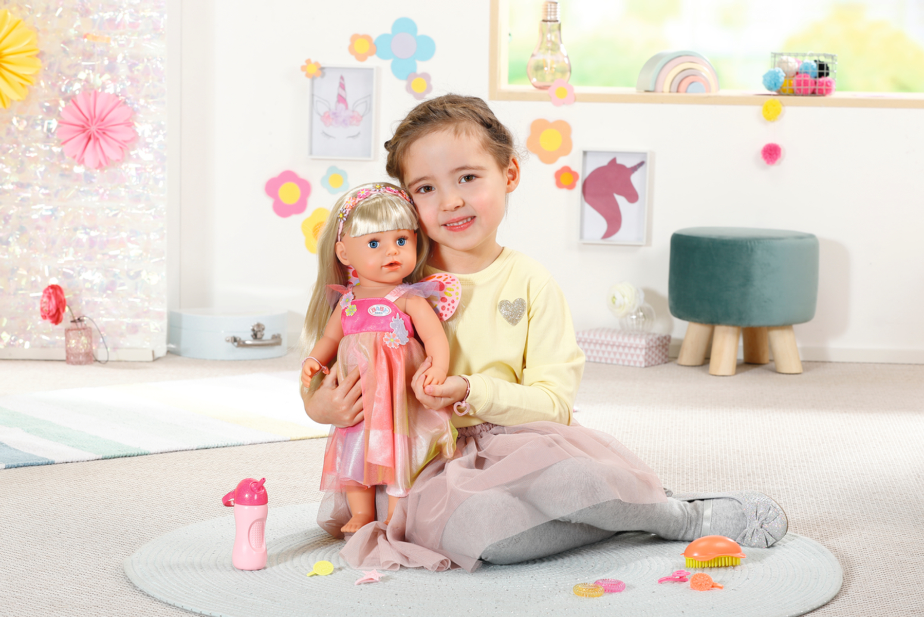 Ein Mädchen hält eine Puppe. Das Mädchen sitzt in einem Raum mit einem Teppich und Spielzeug.