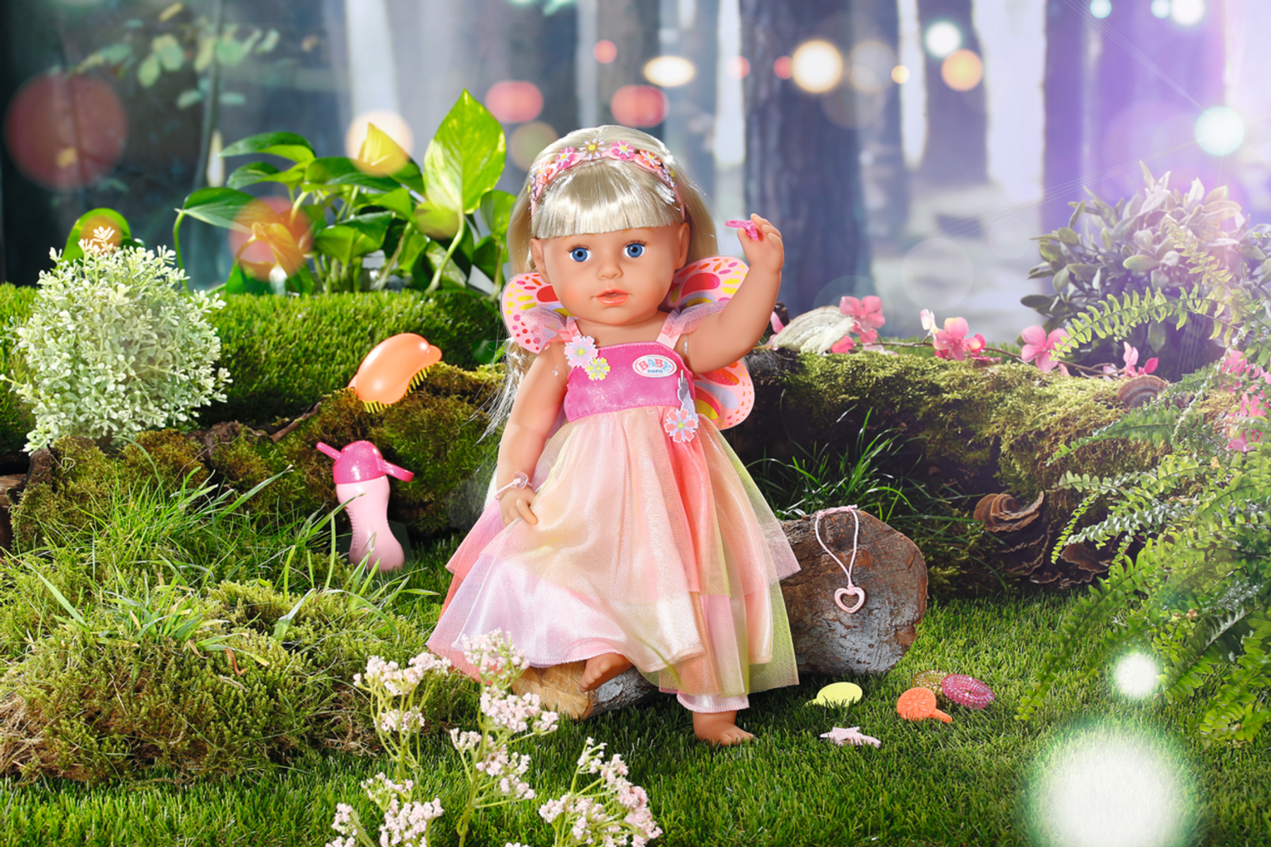 Eine Feenpuppe in einem rosa Kleid steht auf moosigem Boden, umgeben von Blumen und Wald.