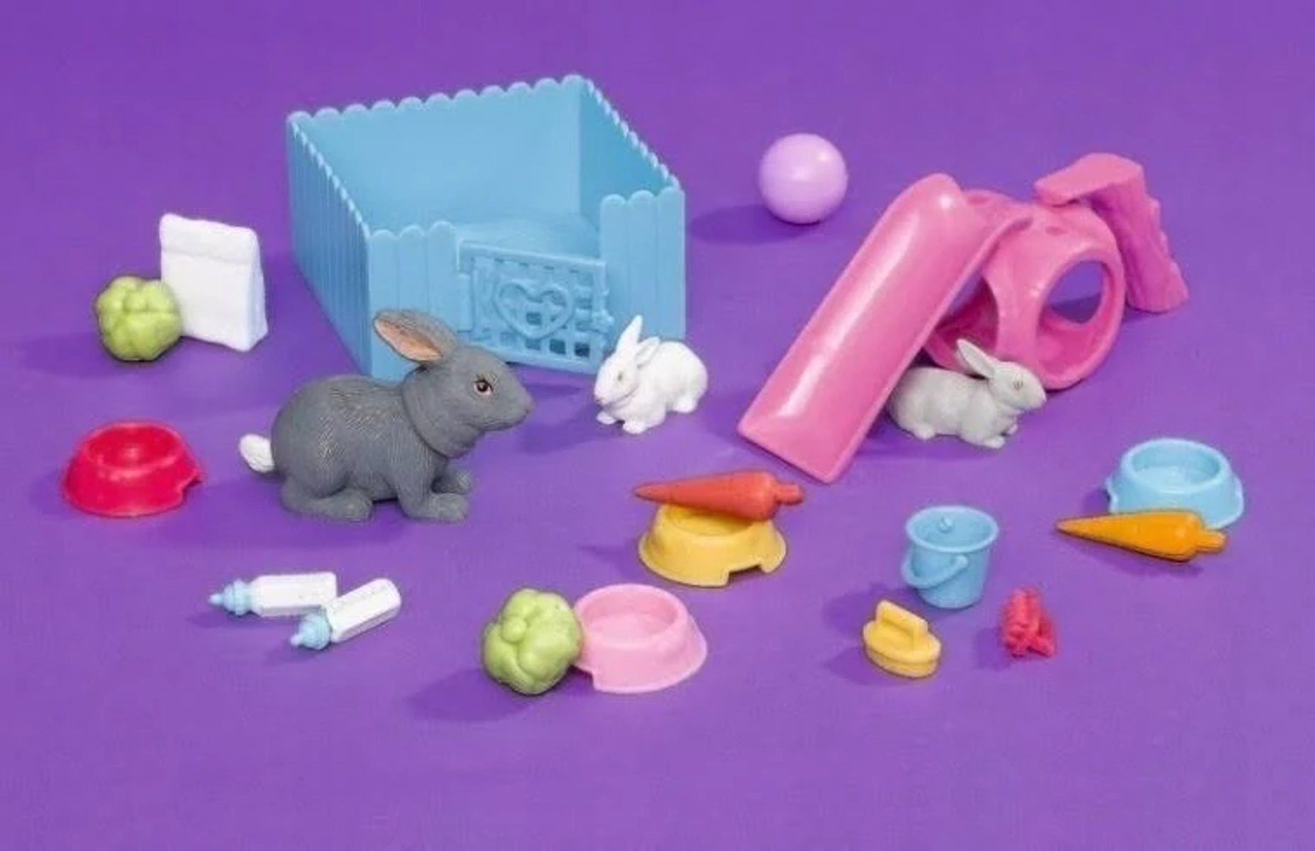 Zabawkowe króliki z akcesoriami: marchewki, miski, klatka, zjeżdżalnia.