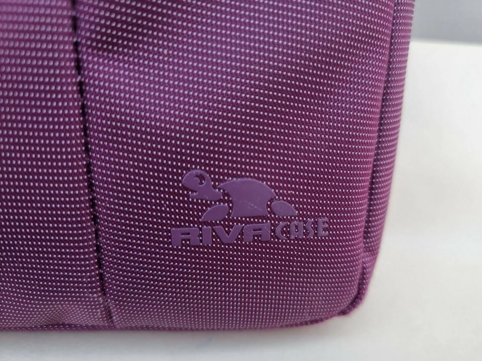 Close-up of a purple fabric bag with the RIVA CASE logo.
