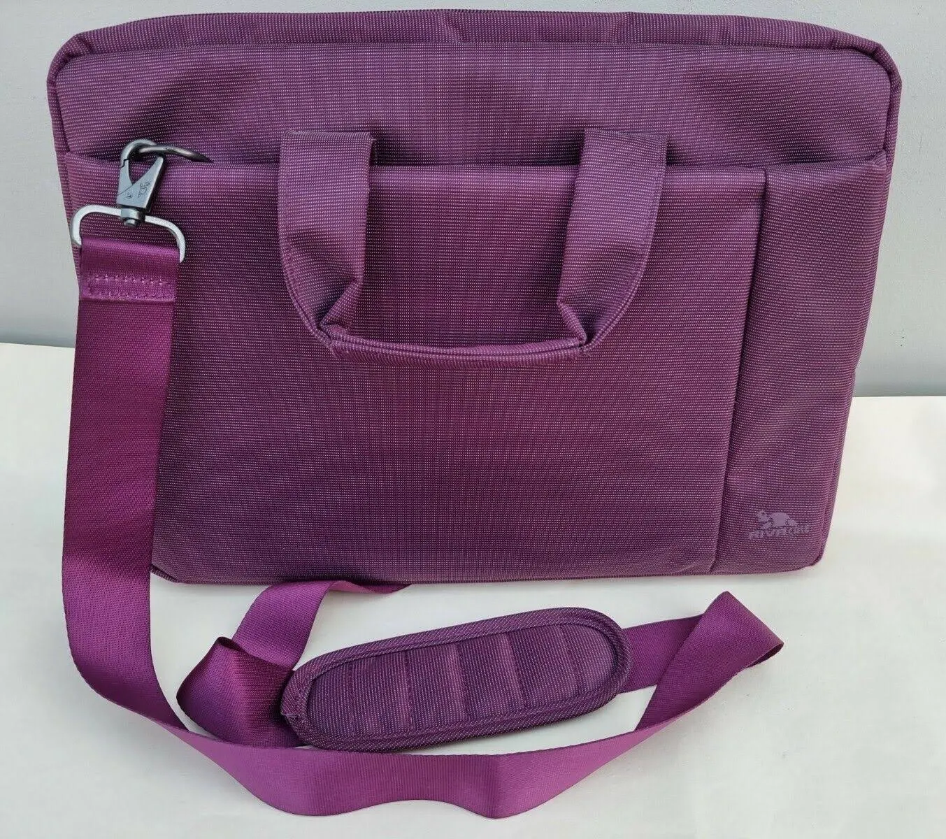 Purple laptop bag with a shoulder strap. The bag has a handle and a side pocket.