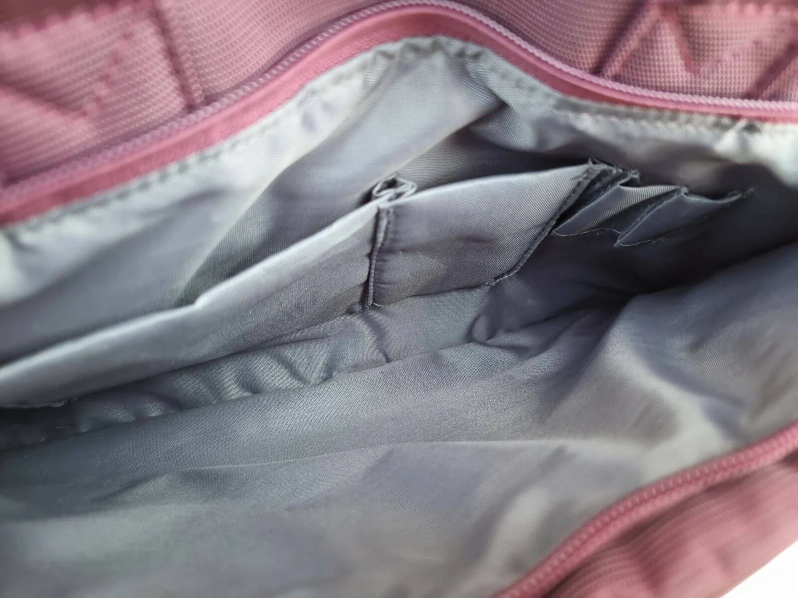 Inside a purple bag, multiple gray pockets are visible. The bag's interior is a lighter shade of gray.