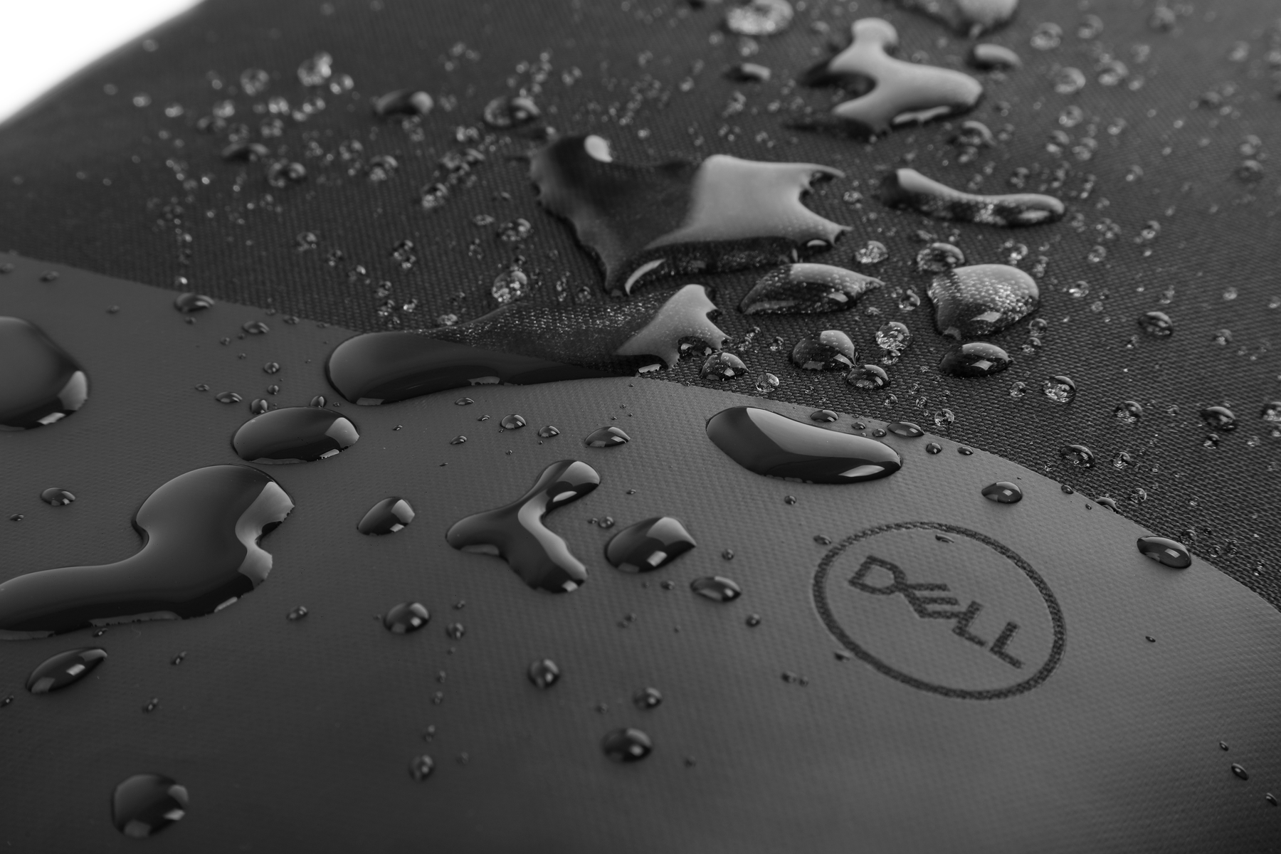 Gocce d'acqua su una superficie nera Dell. Il logo Dell è visibile. Bianco e nero.
