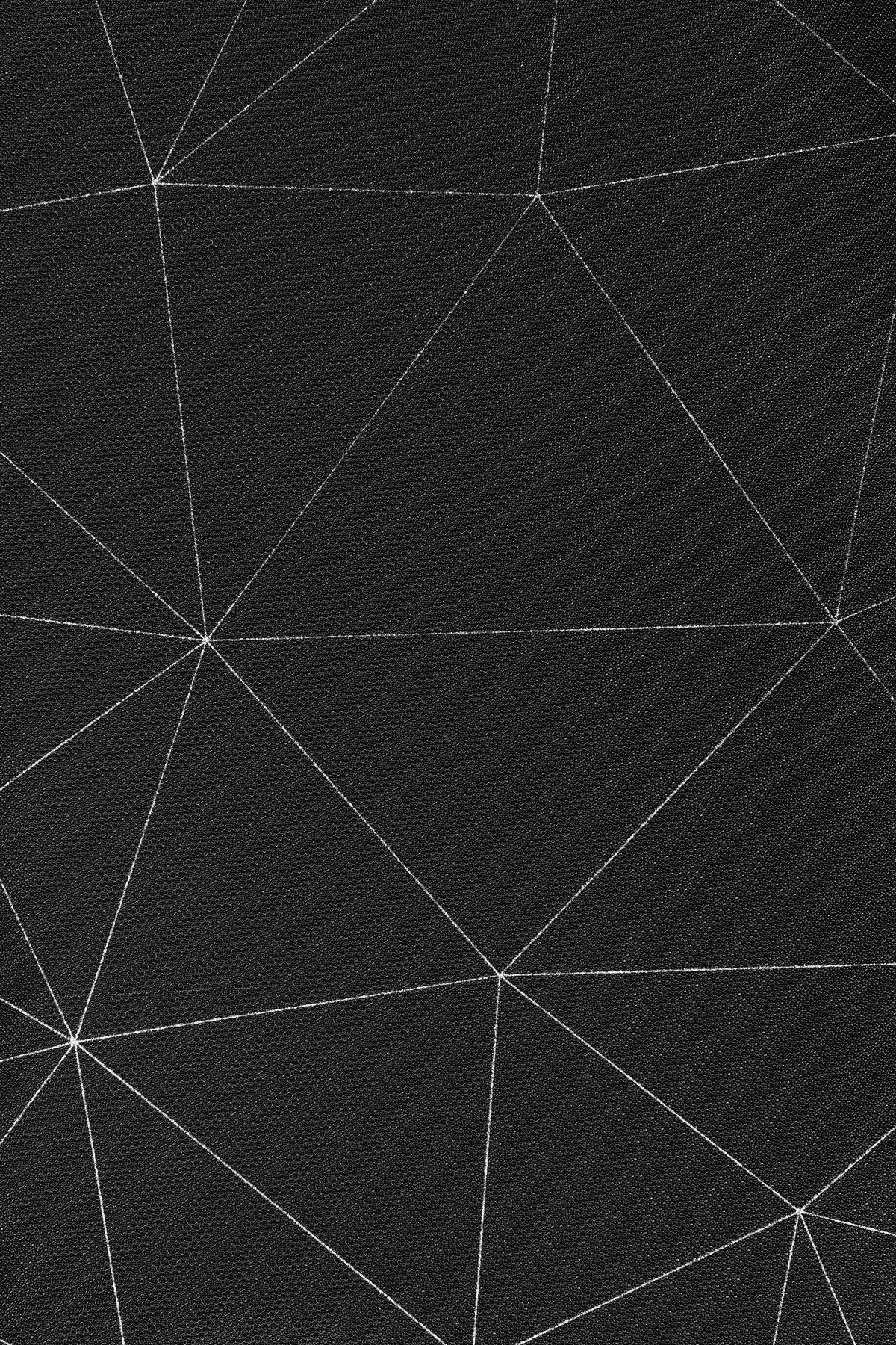 Tessuto nero con un motivo geometrico bianco di linee intersecanti che creano triangoli.