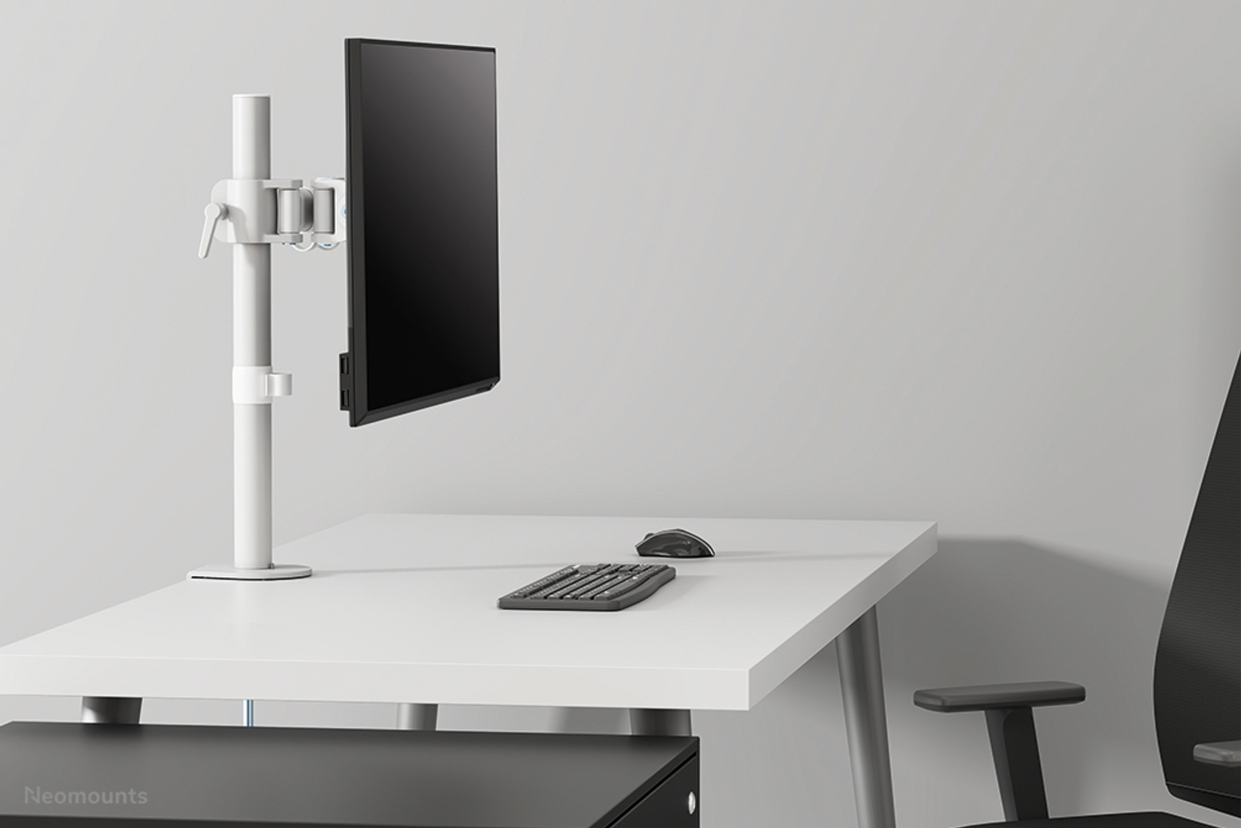 Monitor on a stand with a keyboard and mouse. Set on a white desk.