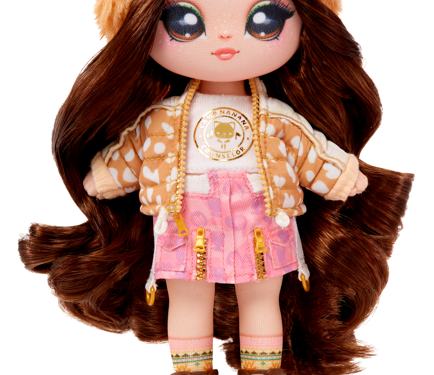 Lalka z brązowymi włosami, w kurtce, spódnicy i czapce. Ma wzór misia.