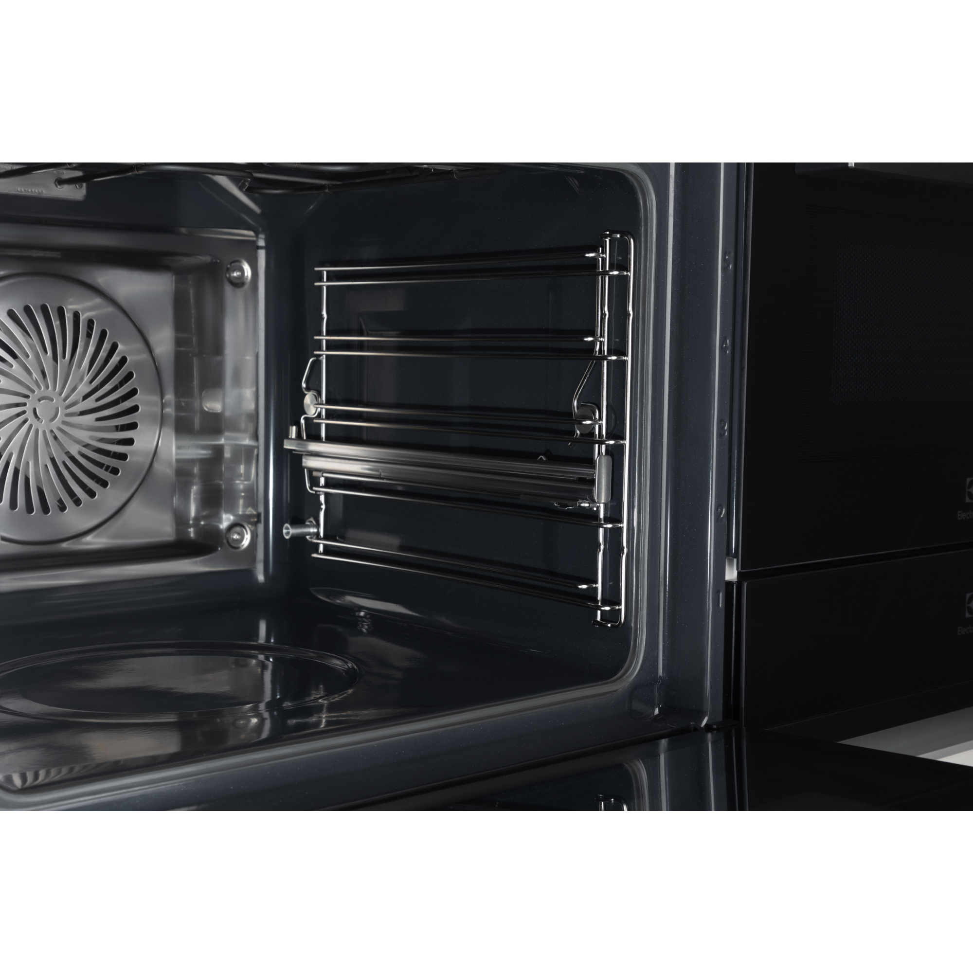 Wnętrze piekarnika. Pokazuje wentylator, ruszty i ciemne wnętrze.