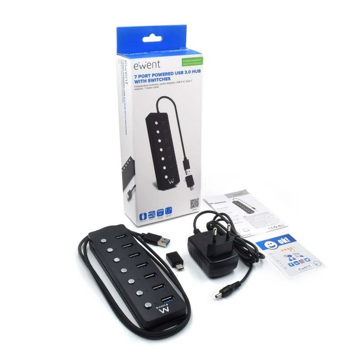 Scatola in bianco e nero con hub USB e accessori, inclusi cavi e un adattatore di alimentazione.