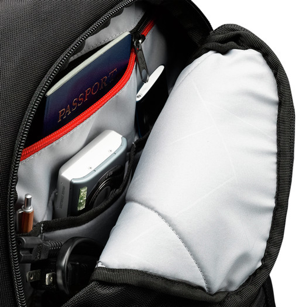 In einem Rucksack mit Reisepass, Kamera, Stift und Ladegerät. Der Innenraum ist grau mit roter Umrandung.