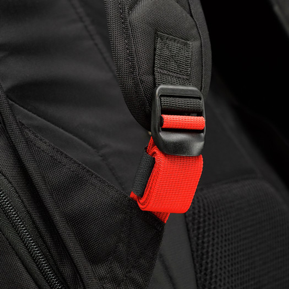 Nahaufnahme eines schwarzen Rucksackgurts mit roter Schnalle.