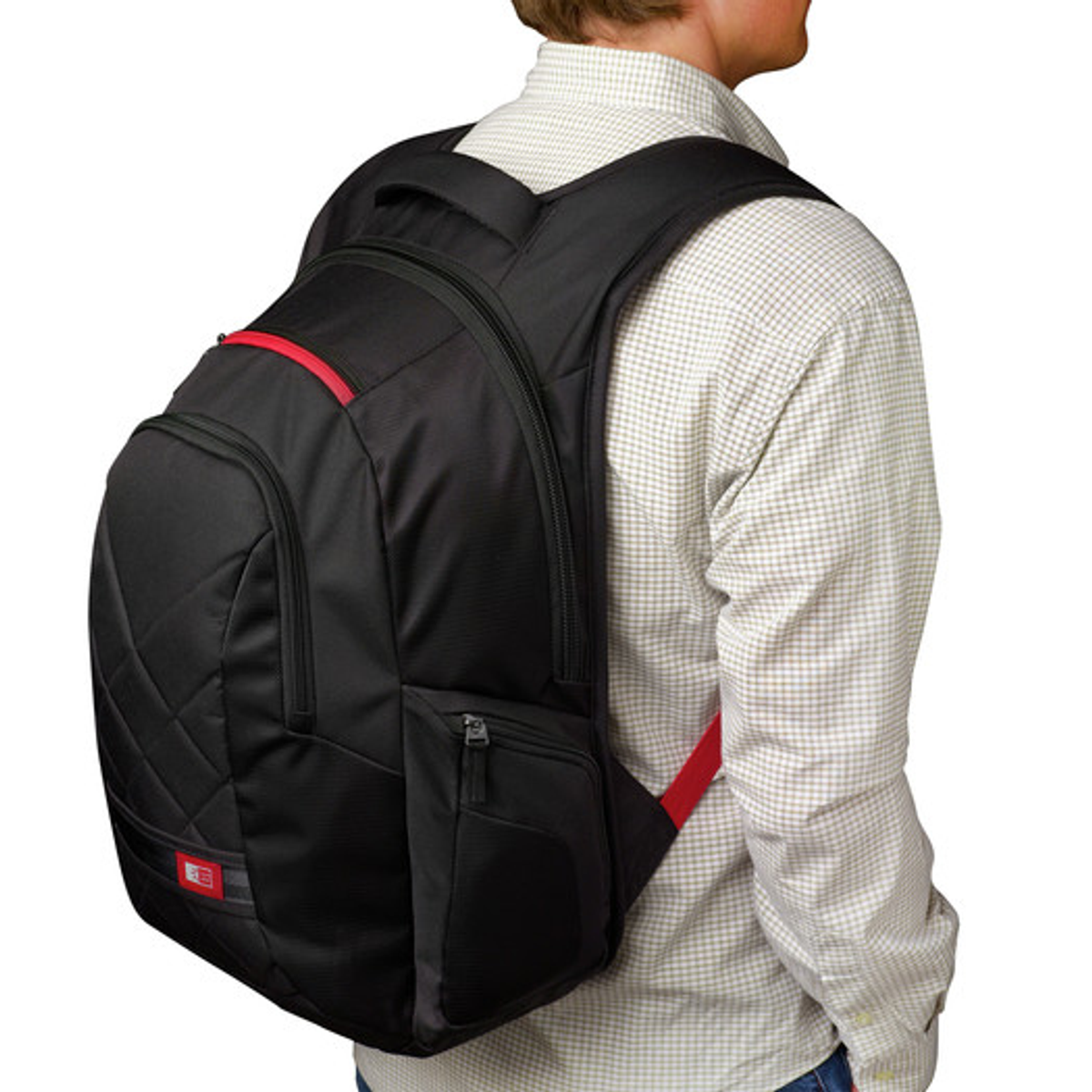 Ein Mann in einem karierten Hemd trägt einen schwarzen Rucksack mit roten Akzenten, der von der Kamera abgewandt ist.