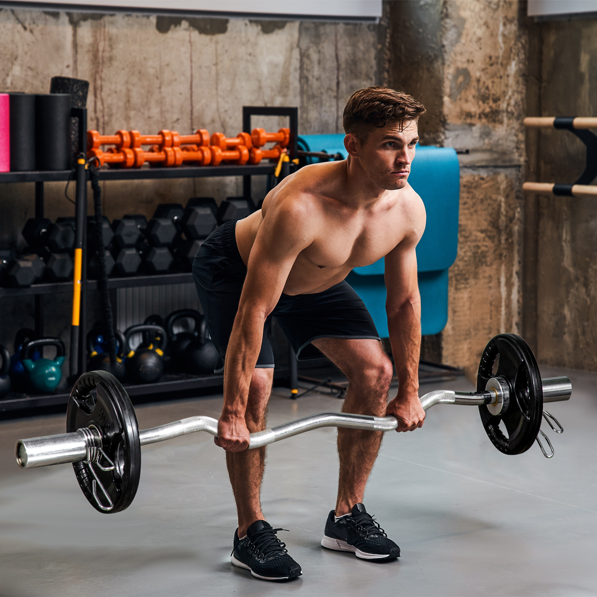 Mann, der eine Langhantel im Fitnessstudio hebt. Gewichte sind auf der Stange.