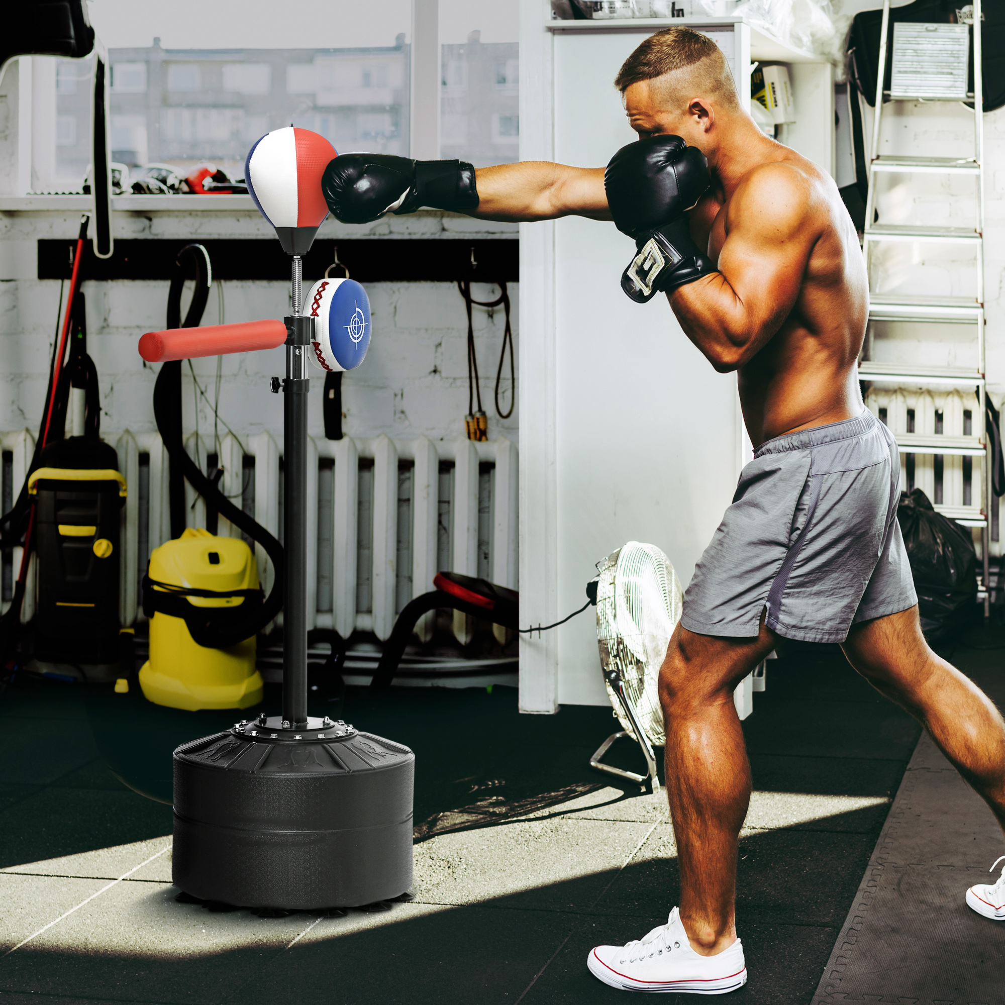 Uomo colpisce un sacco da boxe in palestra con attrezzi sullo sfondo.