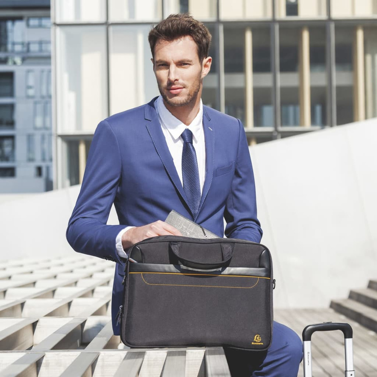 Hombre en traje azul sosteniendo un maletín negro.