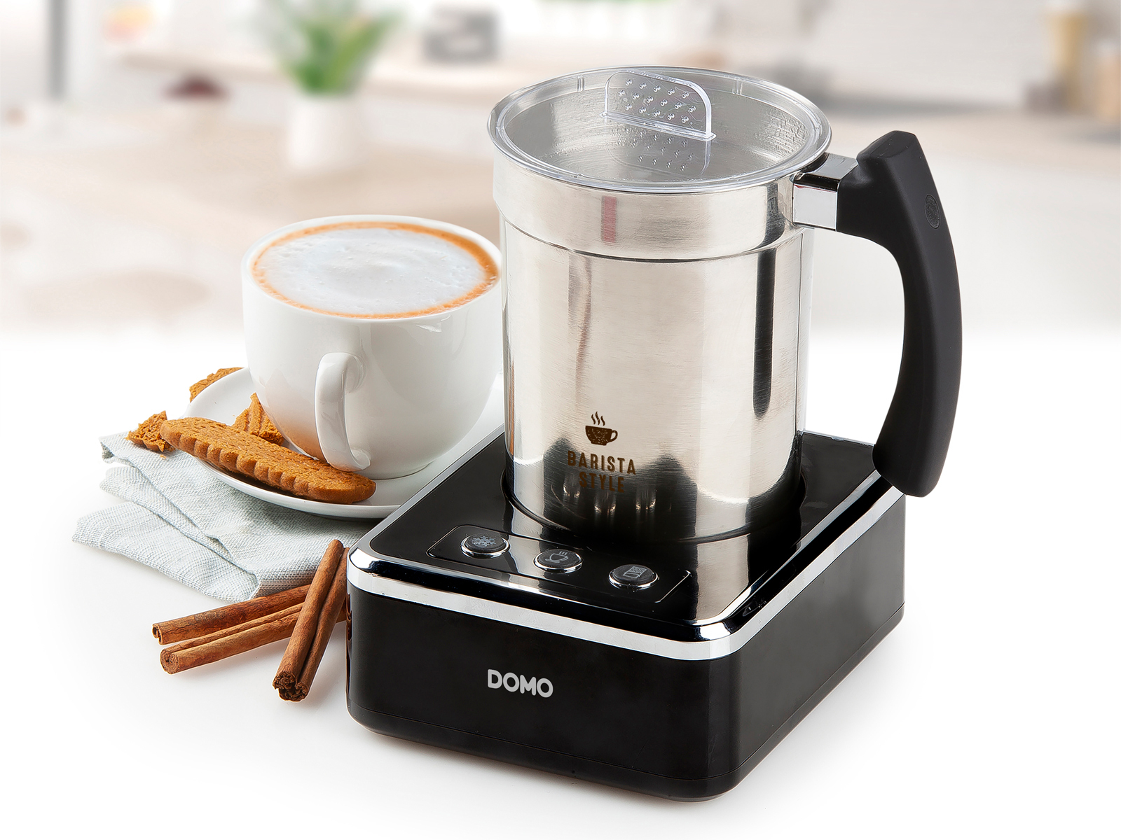 Spieniacz do mleka ze stali nierdzewnej z czarną podstawą, filiżanka kawy i laski cynamonu.