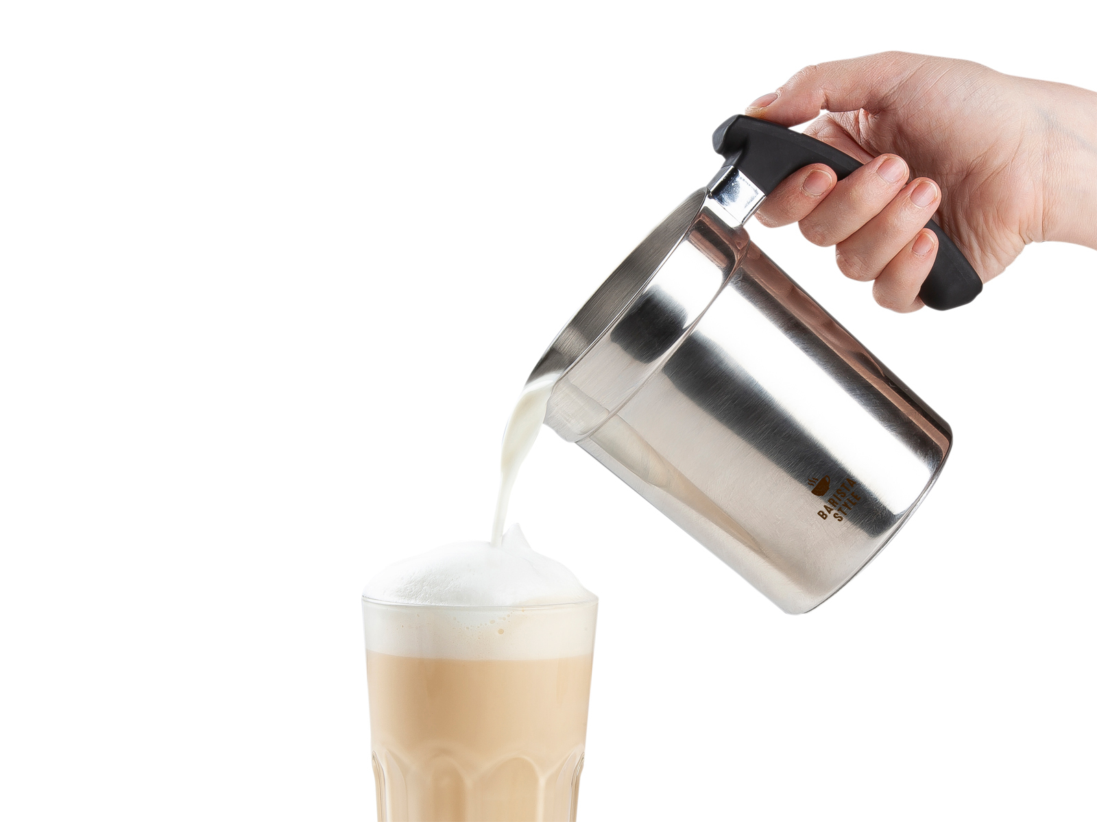 Ręka nalewa mleko ze srebrnego dzbanka do szklanki kawy. Kawa ma pianę.