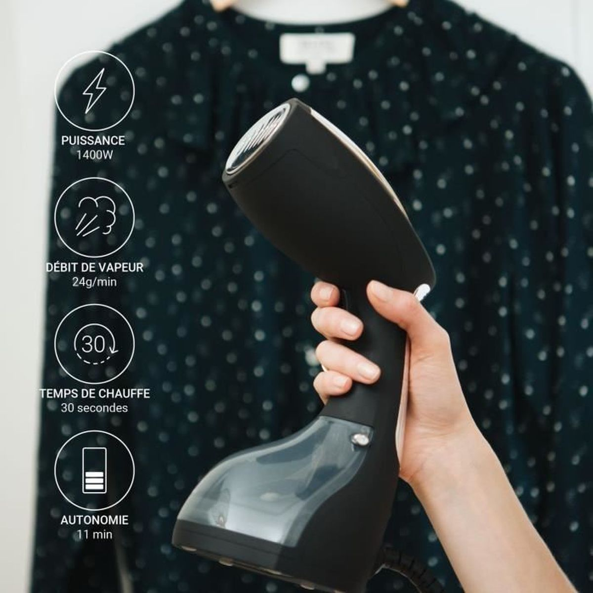 Une main tenant un défroisseur de vêtements noir. L'arrière-plan est une chemise sombre.