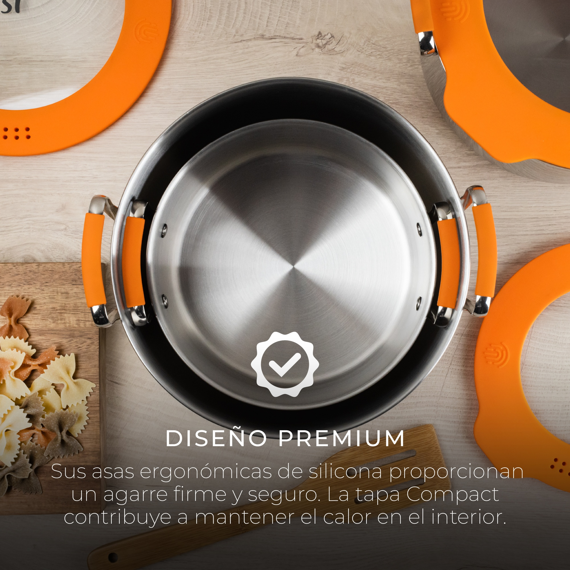 Ollas con asas y tapas naranjas. Una olla está dentro de otra sobre una superficie de madera.