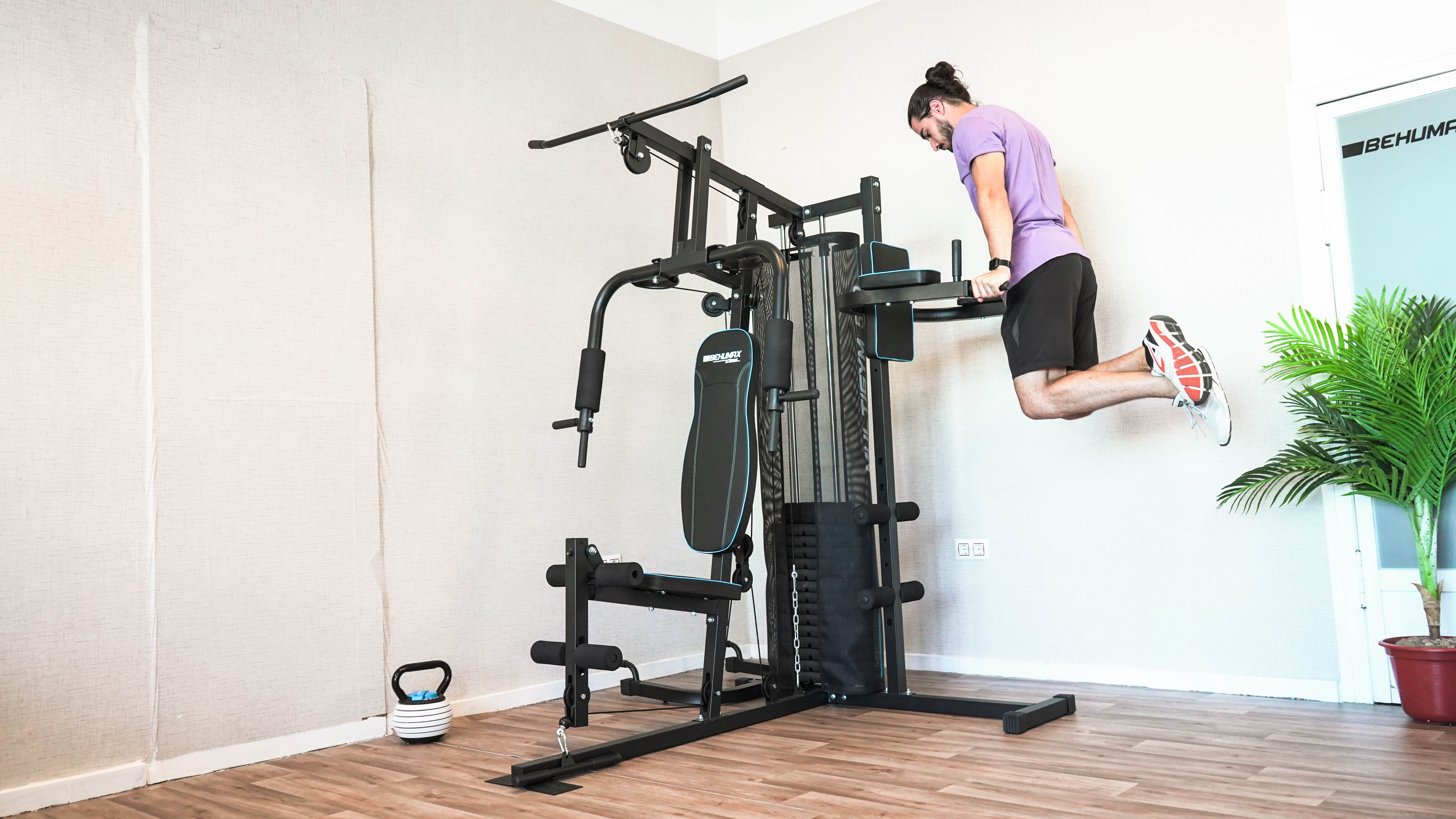 Hombre haciendo flexiones en una máquina de ejercicios. Una pesa rusa en el suelo. Interior del gimnasio.