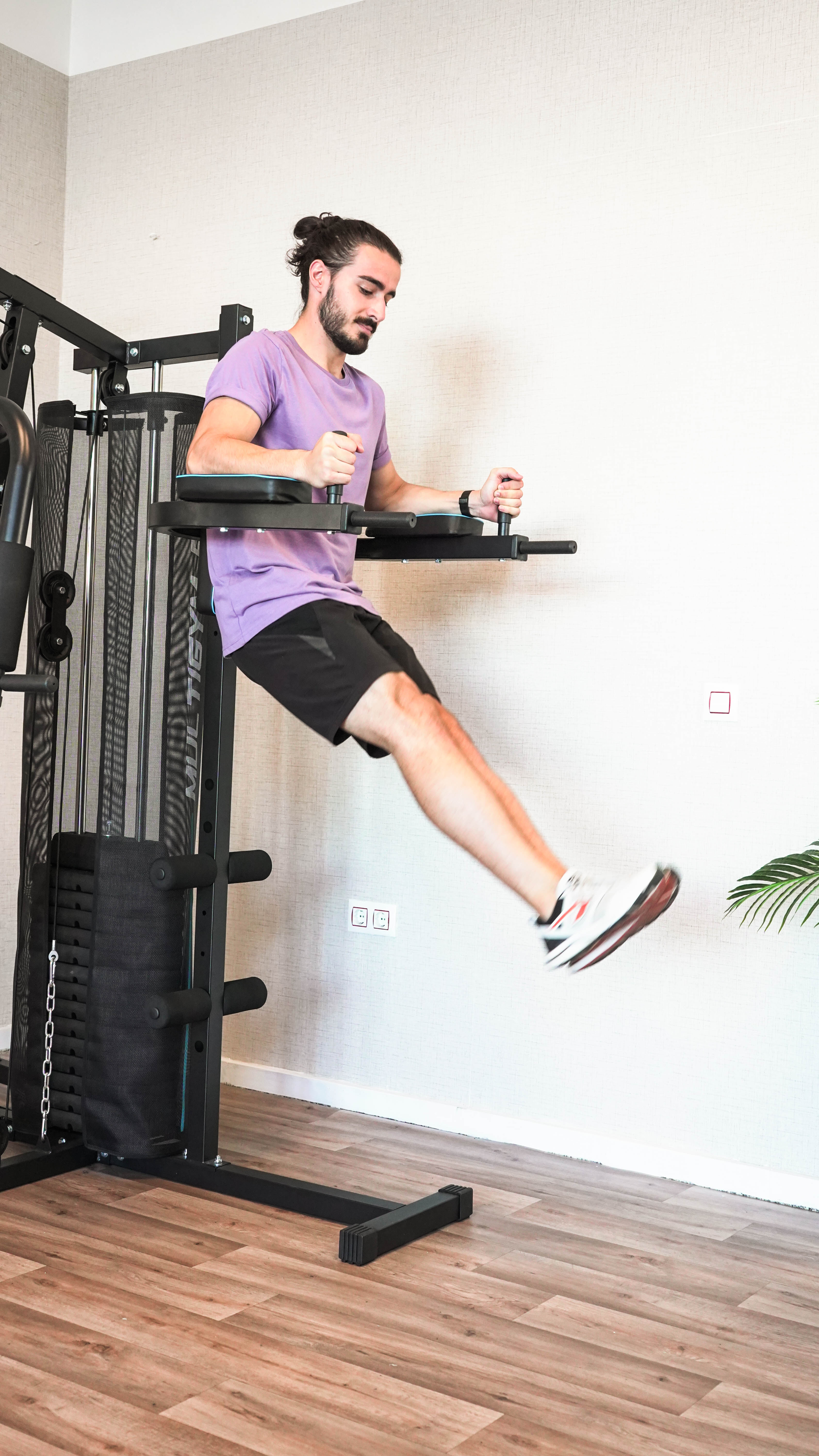 Hombre en el gimnasio. Está haciendo ejercicio en una máquina multigimnasio. El hombre hace elevaciones de piernas.