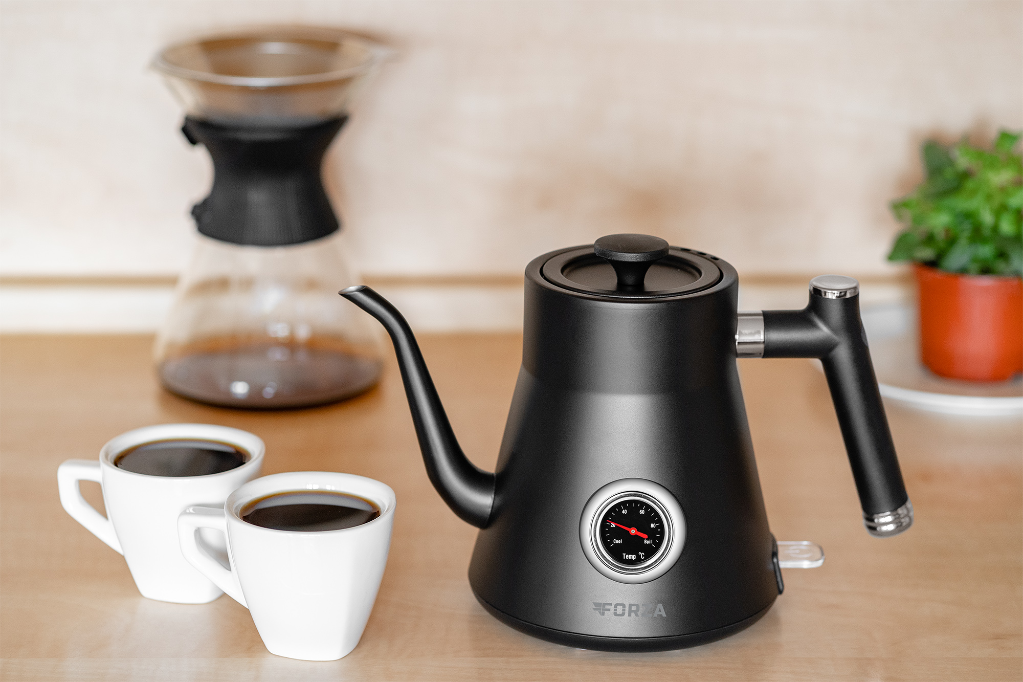 Schwarzer Wasserkocher mit Schwanenhalsauslauf, zwei Tassen Kaffee und ein Pour-Over-Kaffeebereiter.