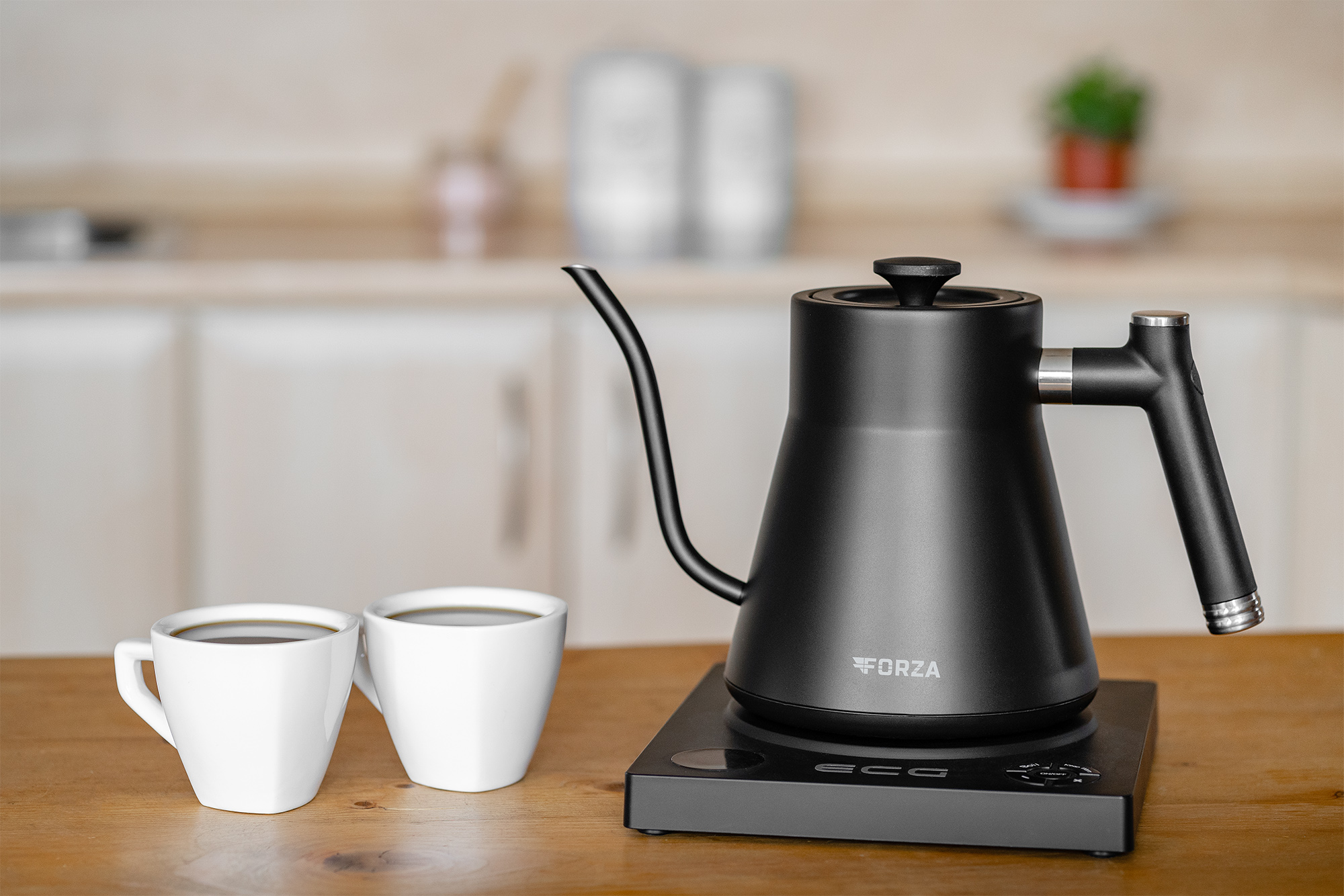 Schwarzer Schwanenhalskessel auf schwarzem Sockel mit zwei weißen Kaffeetassen auf Holztisch.
