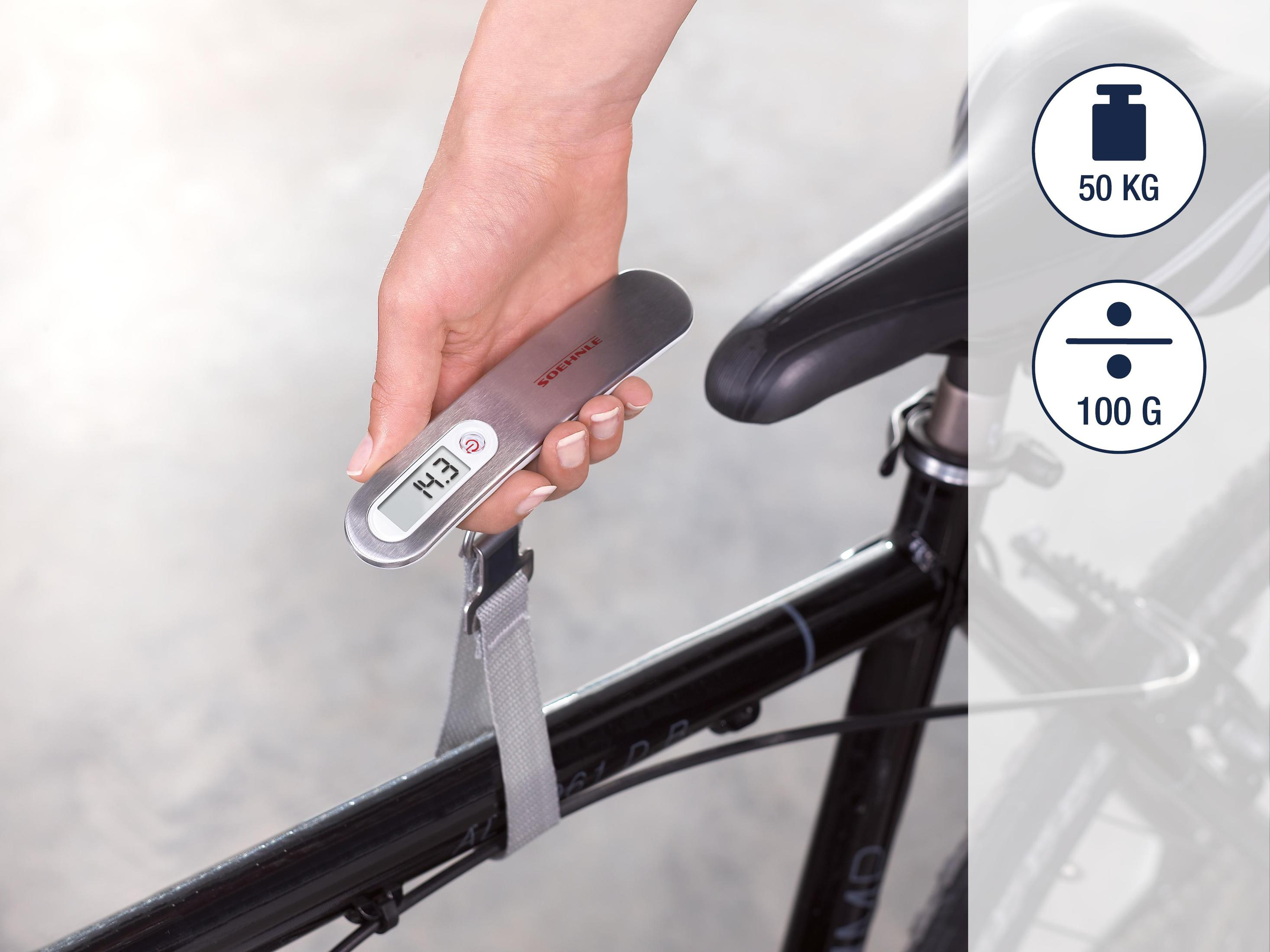 Persona che pesa una bici con una bilancia. Testo: 14,3, 50 kg, 100 g.