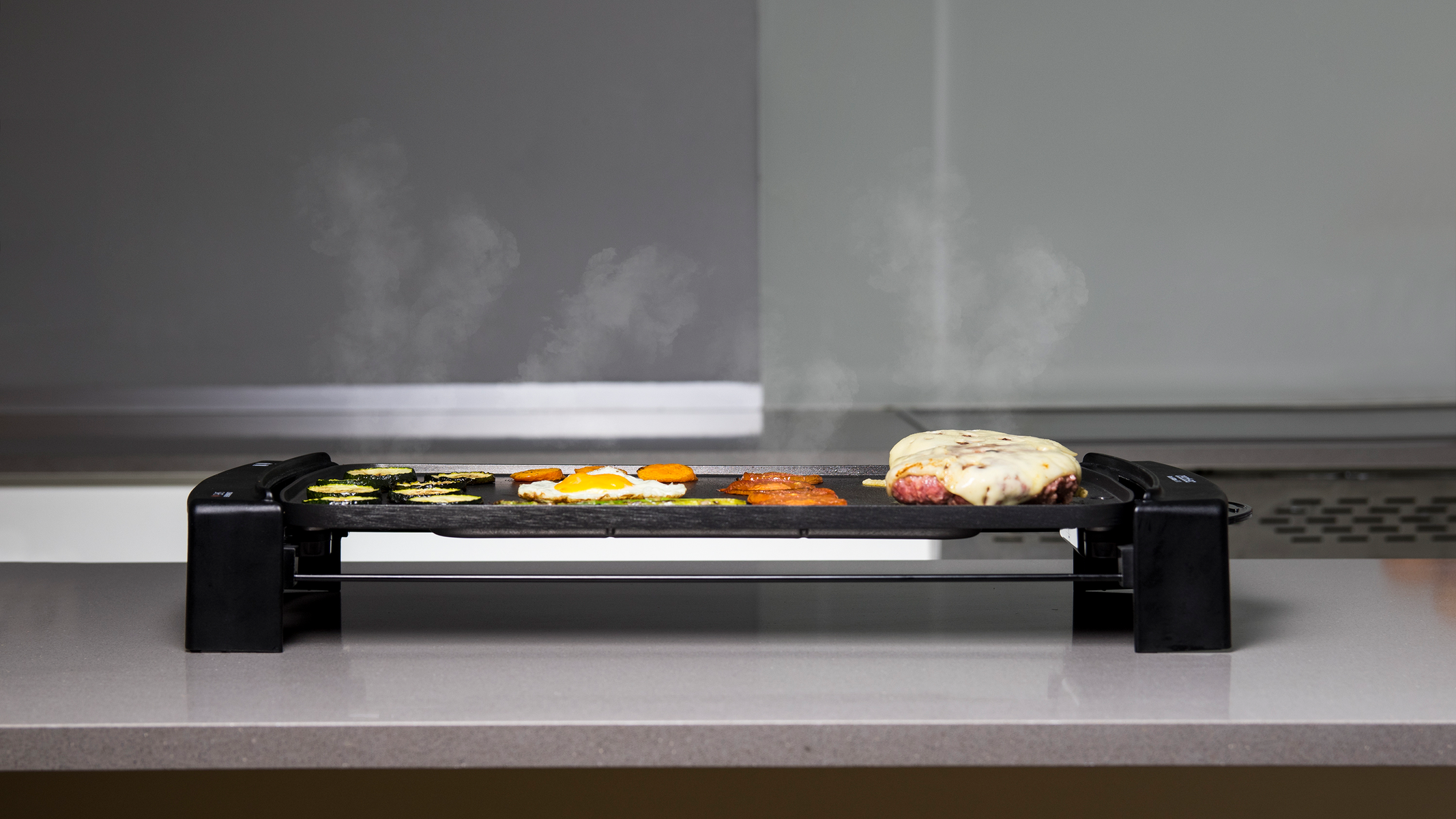Una parrilla eléctrica con comida cocinándose, con un fondo blanco y gris.