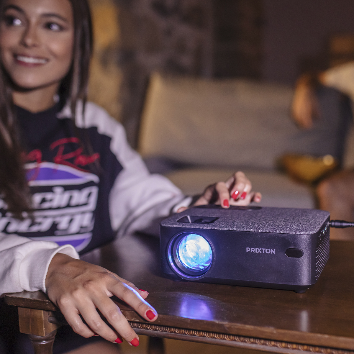 Kobieta obsługuje projektor, rzucając niebieskie światło na ciemnoszarą powierzchnię.