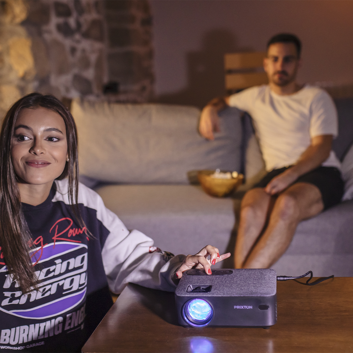 Kobieta i mężczyzna oglądają ekran projektora w salonie.